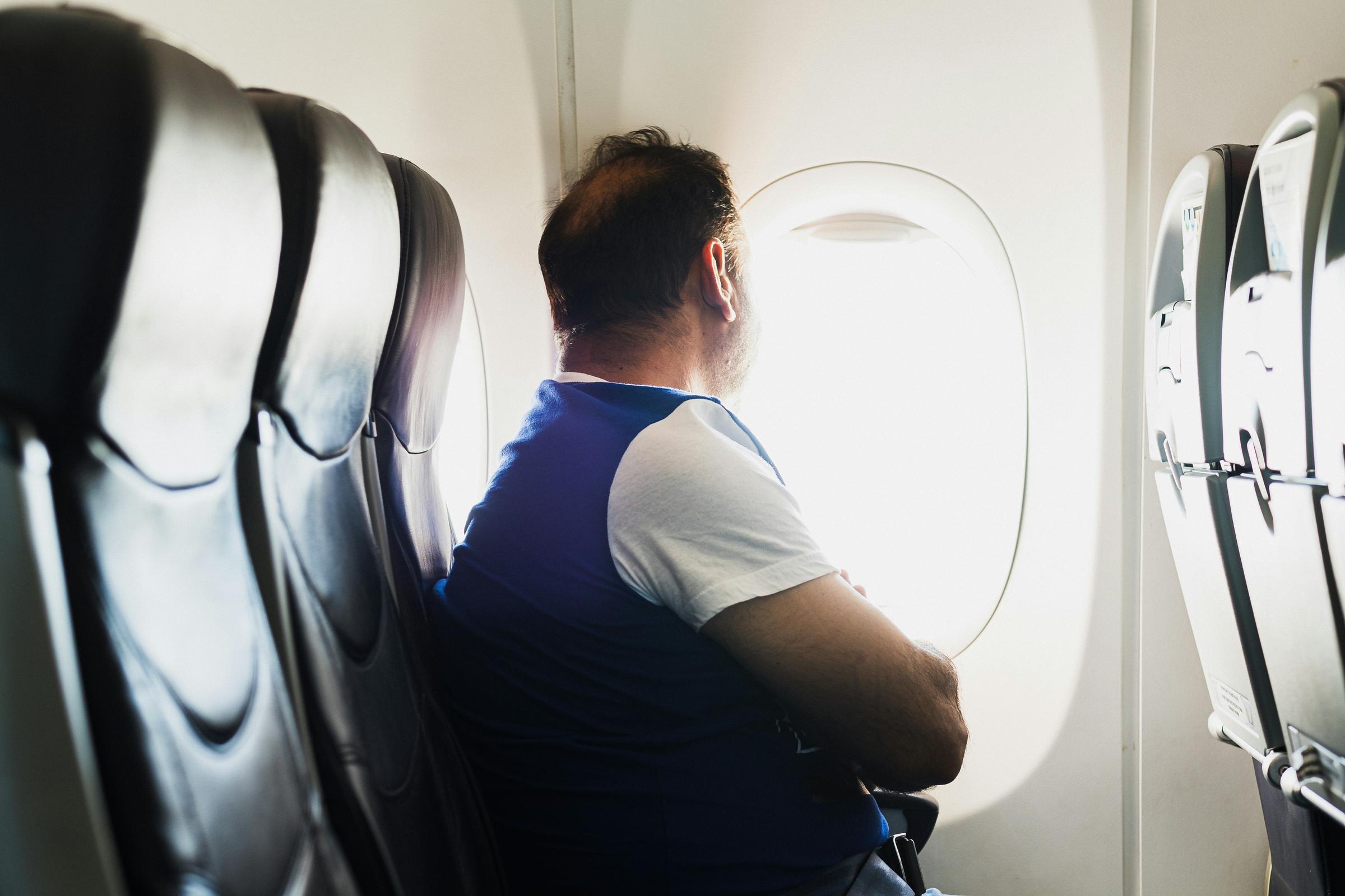 Un homme à l'intérieur d'un avion regardant par le hublot | Source : Unsplash
