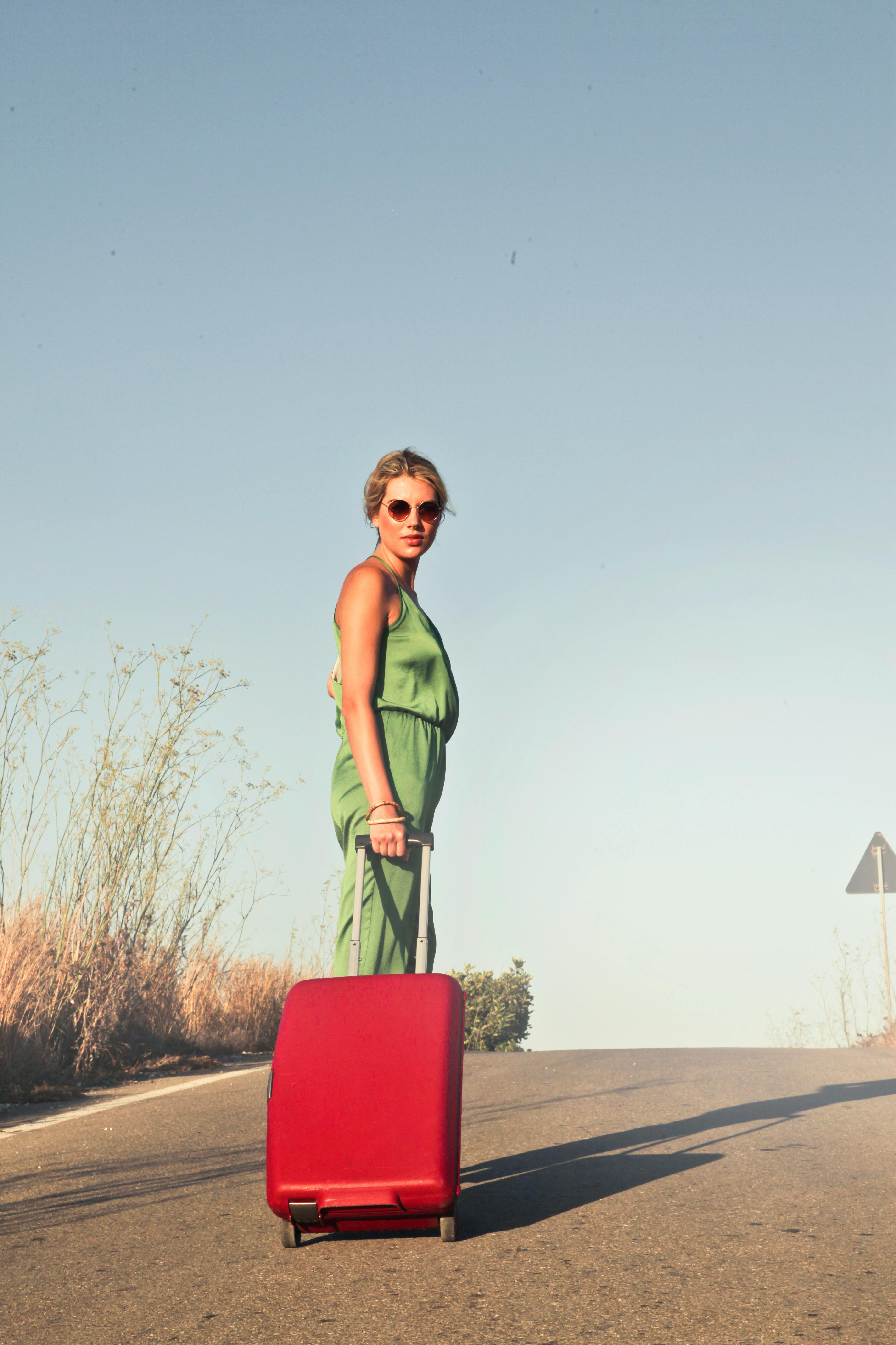 Une femme marchant avec une valise rouge | Source : Pexels