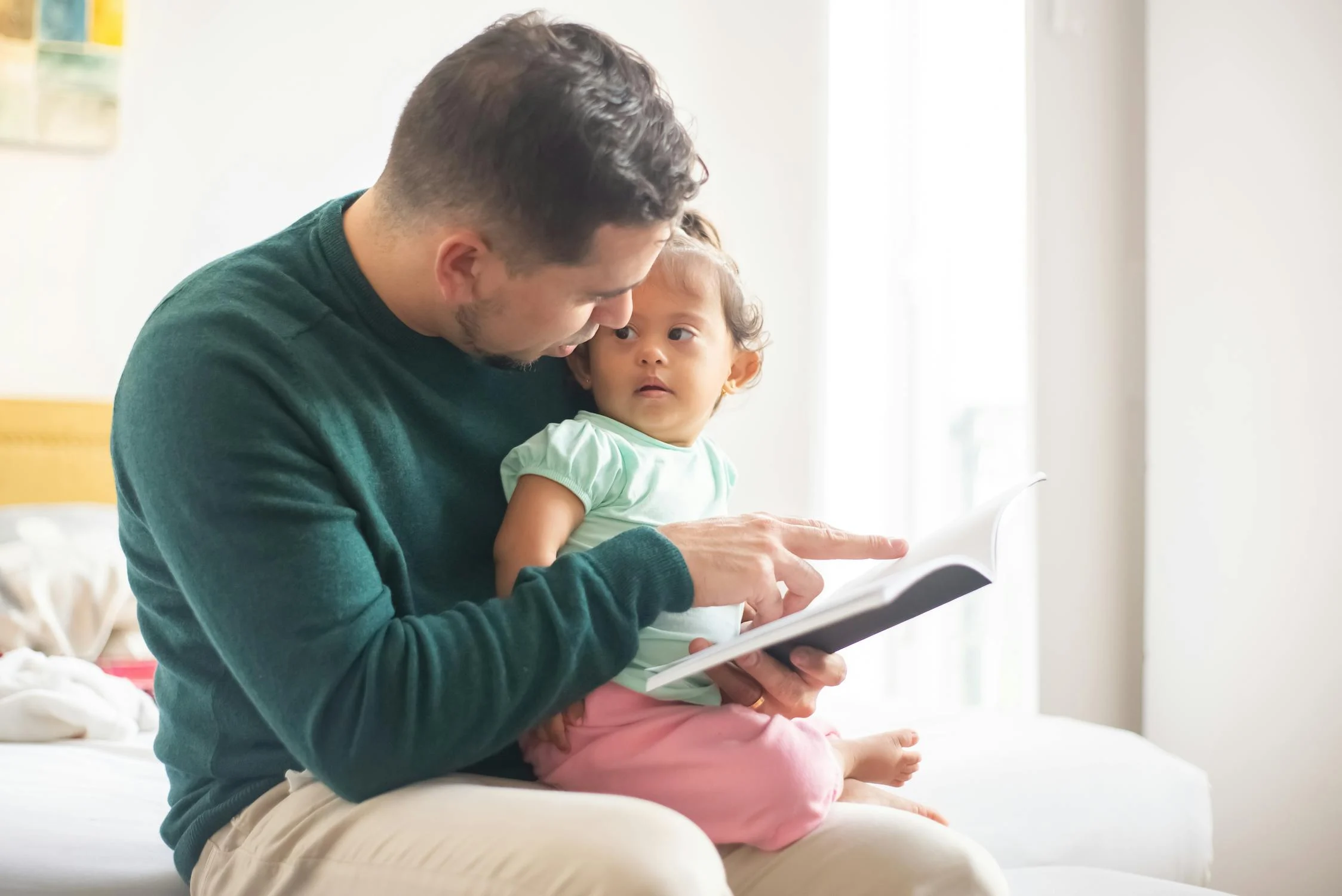 Un homme lisant un livre à sa fille | Source : Pexels