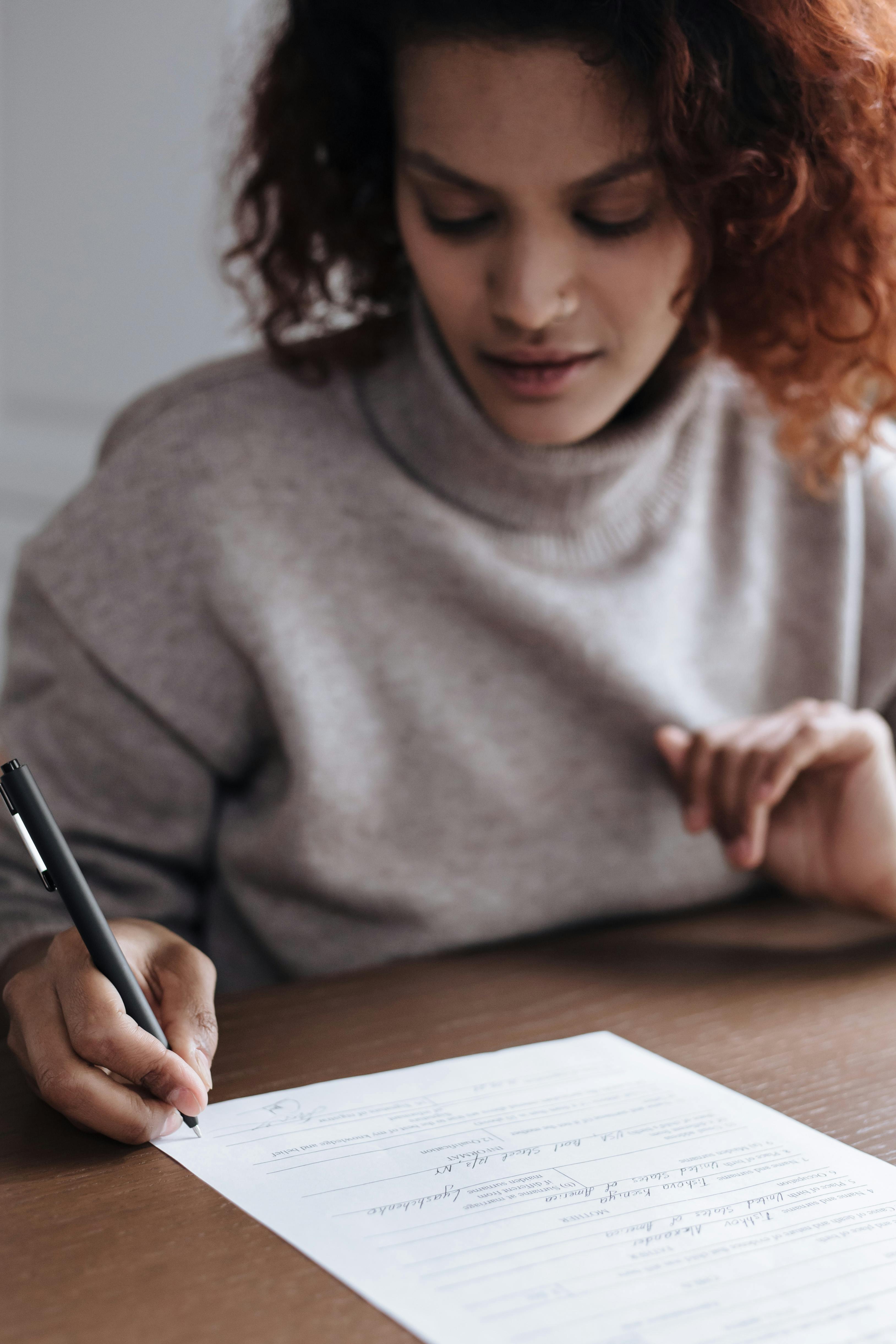 Une femme signant des documents | Source : Pexels