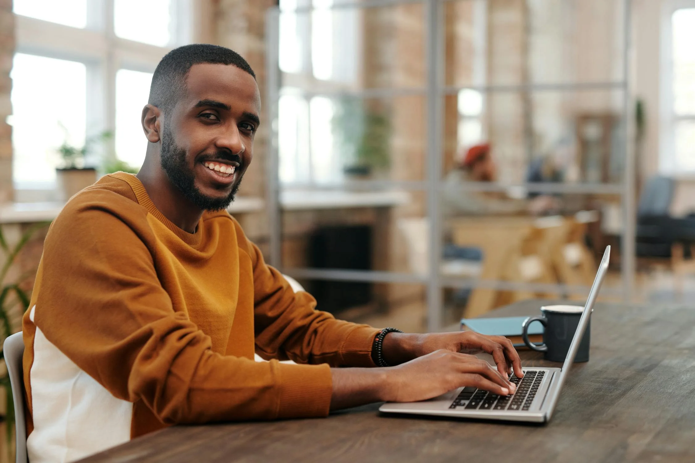 Un homme souriant avec un ordinateur portable | Source : Pexels