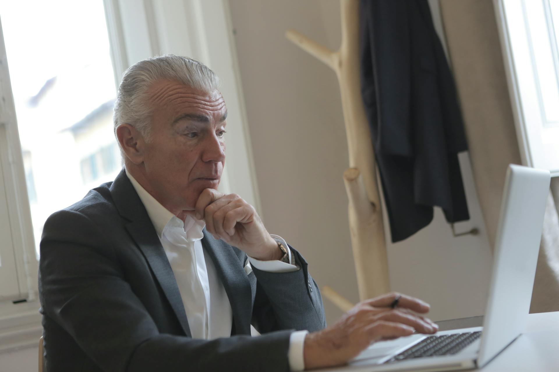 Un homme élégant d'un certain âge utilise son ordinateur portable dans son bureau | Source : Pexels