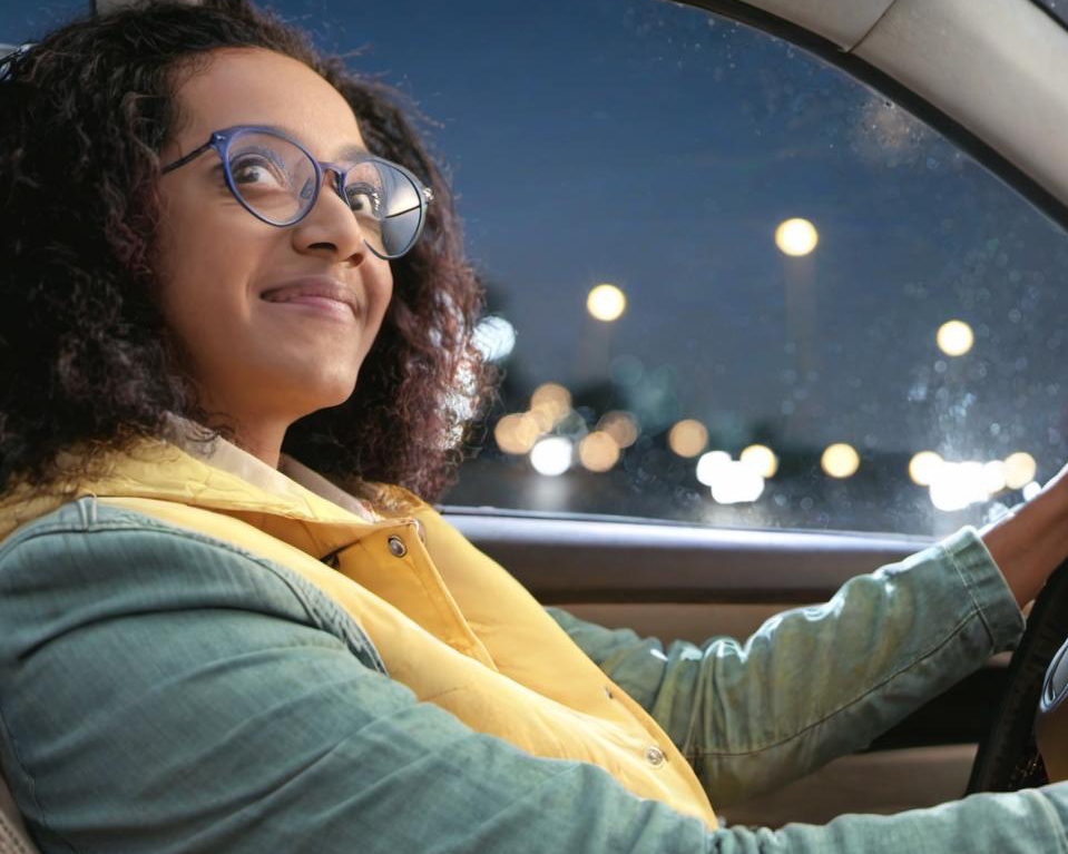 A woman smiles contentedly while driving | Source: Midjourney