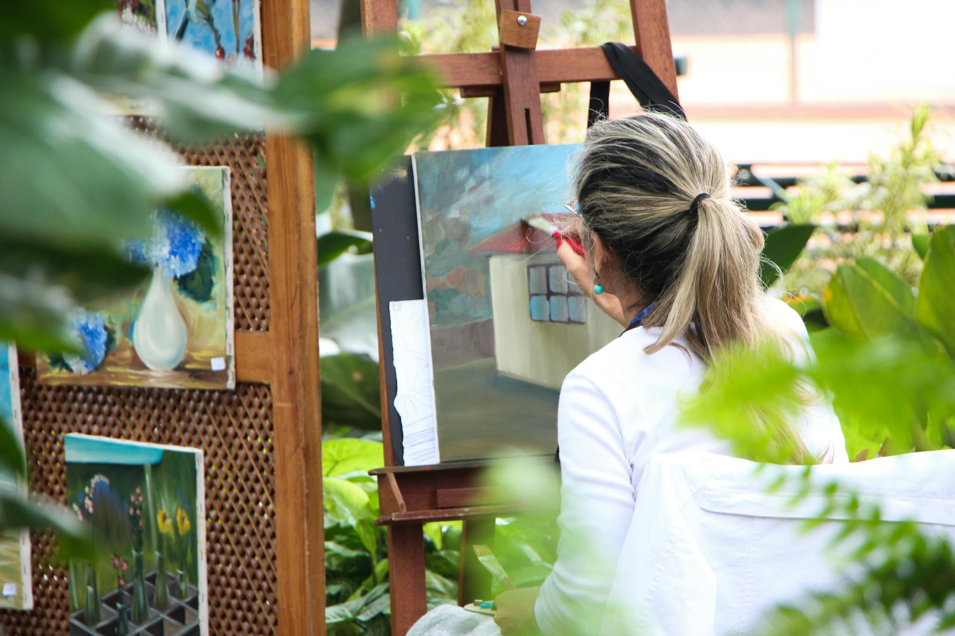 Vue arrière d'une femme en train de peindre un tableau dans le jardin | Source : Pexels