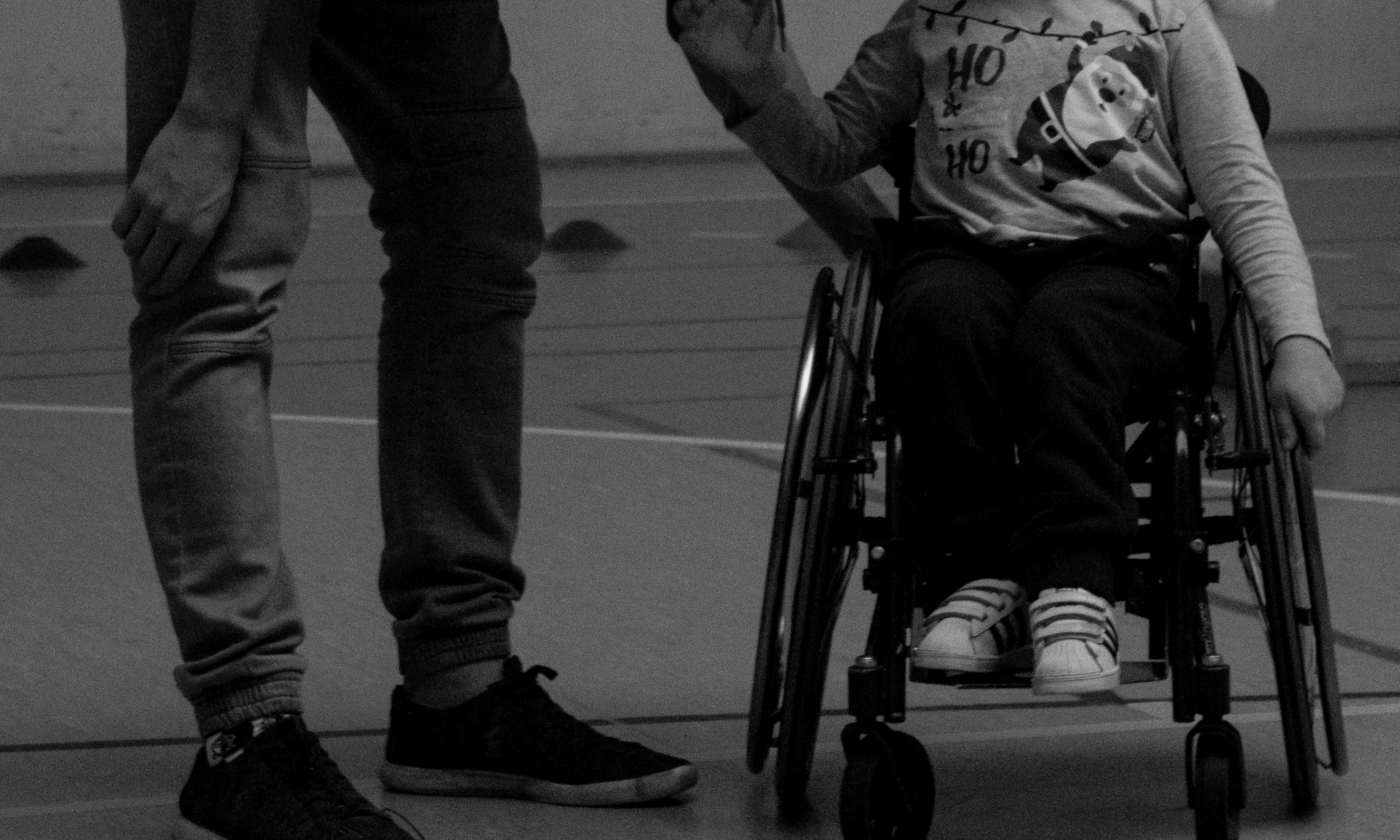 Un homme se penche pour parler à un garçon en fauteuil roulant | Source : Pexels