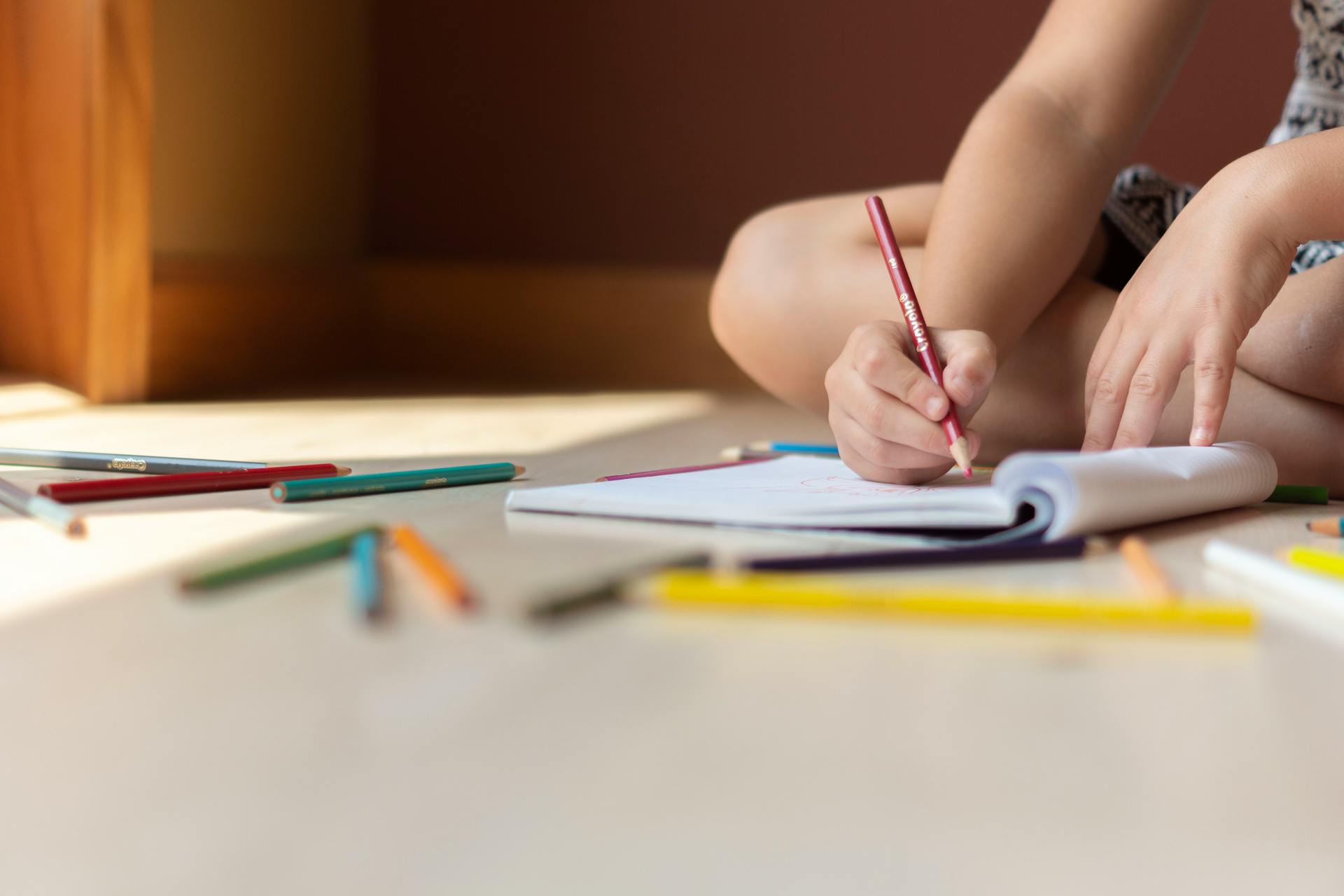 Un enfant assis par terre et qui dessine | Source : Pexels