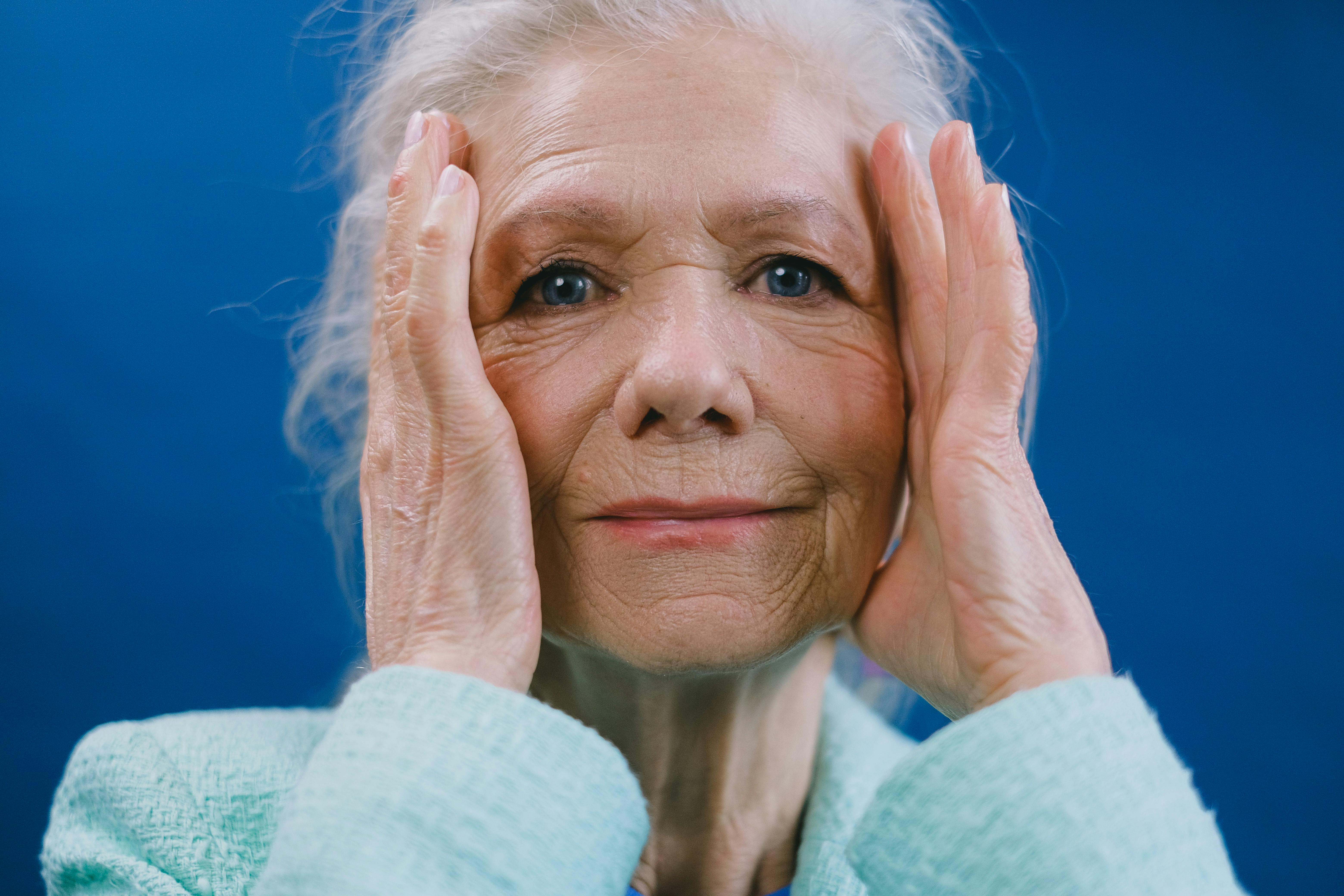 Une femme âgée avec ses mains de chaque côté de sa tête | Source : Pexels