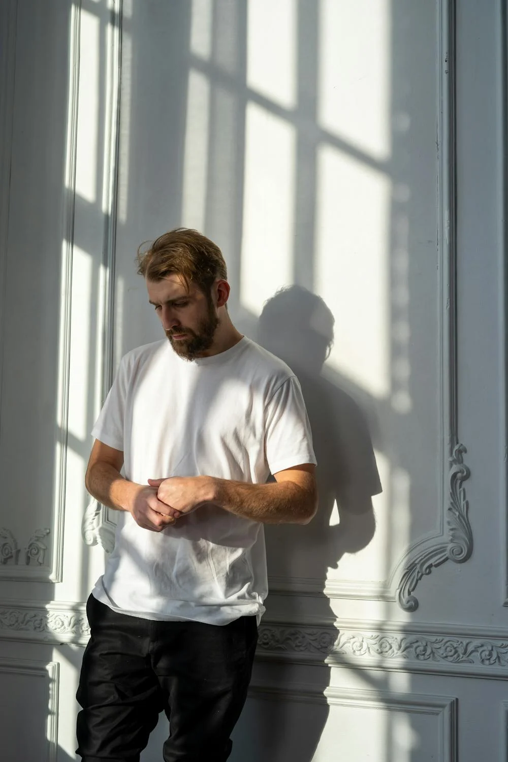 A quiet man standing near a wall ⏐ Source: Pexels