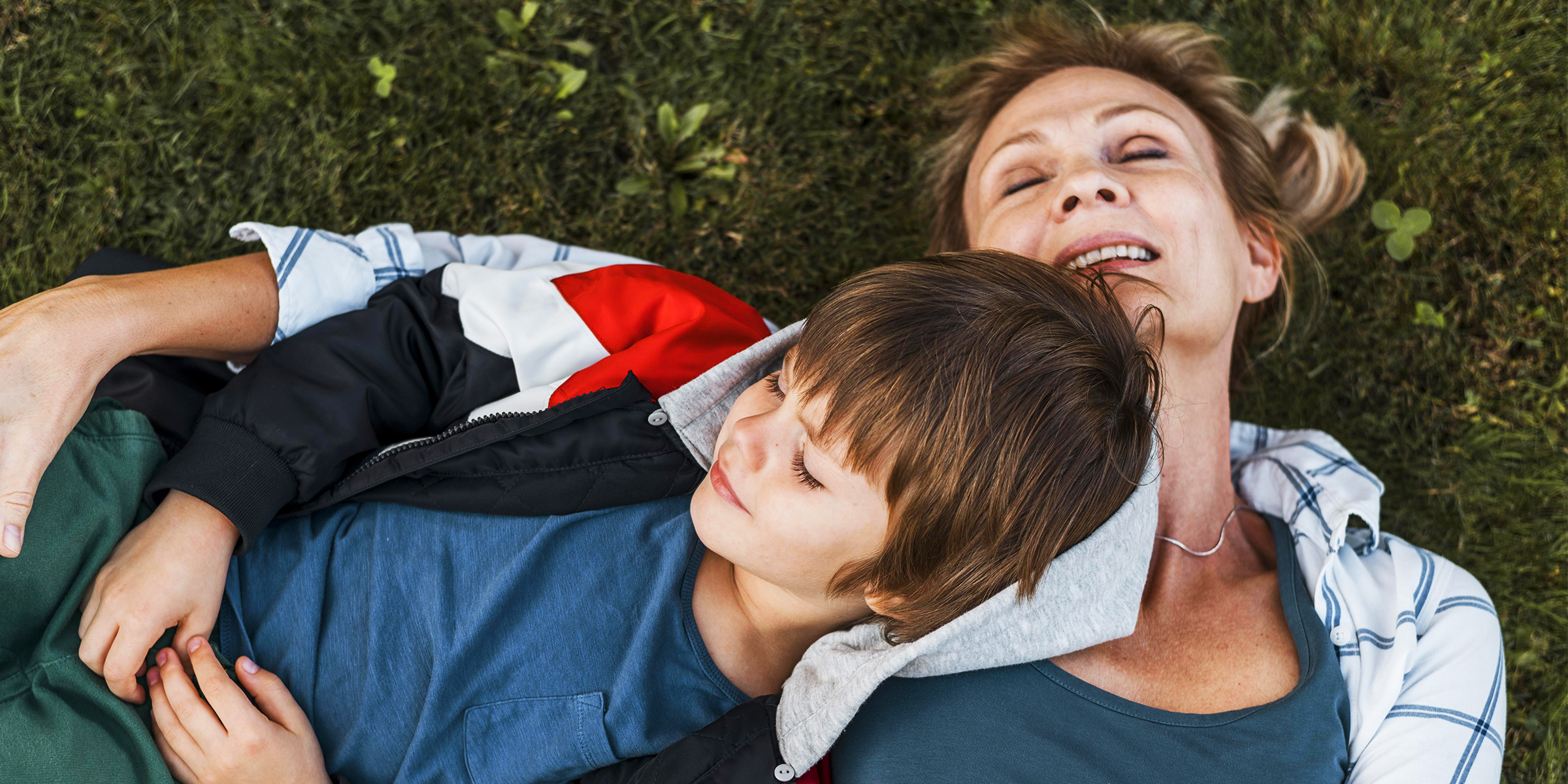 Une femme allongée sur une pelouse avec son fils | Source : freepik.com/freepik