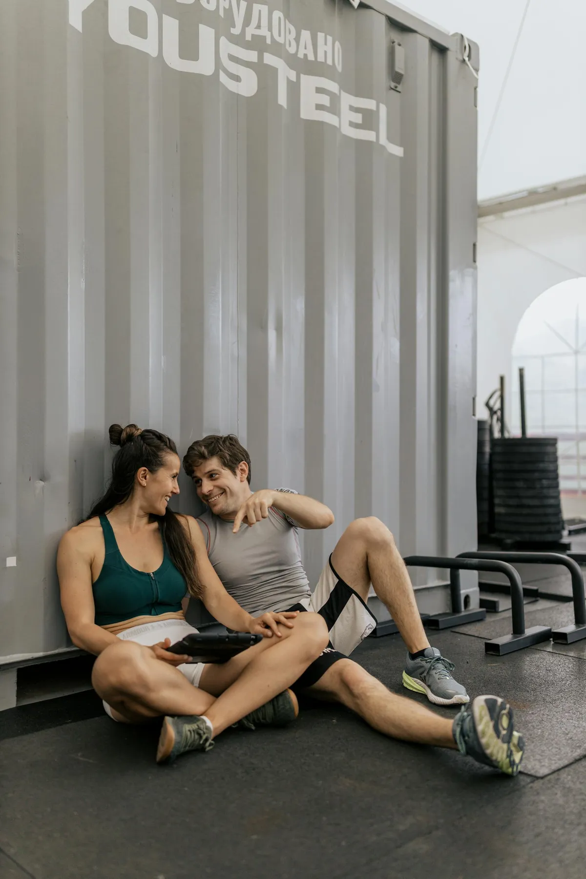 Un couple en tenue de sport assis par terre et discutant | Source : Pexels