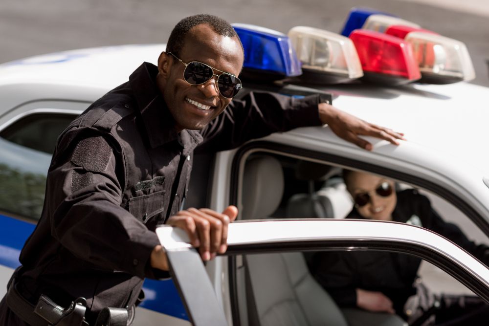 Deux policiers sourient près de leur voiture. | Source : Shutterstock