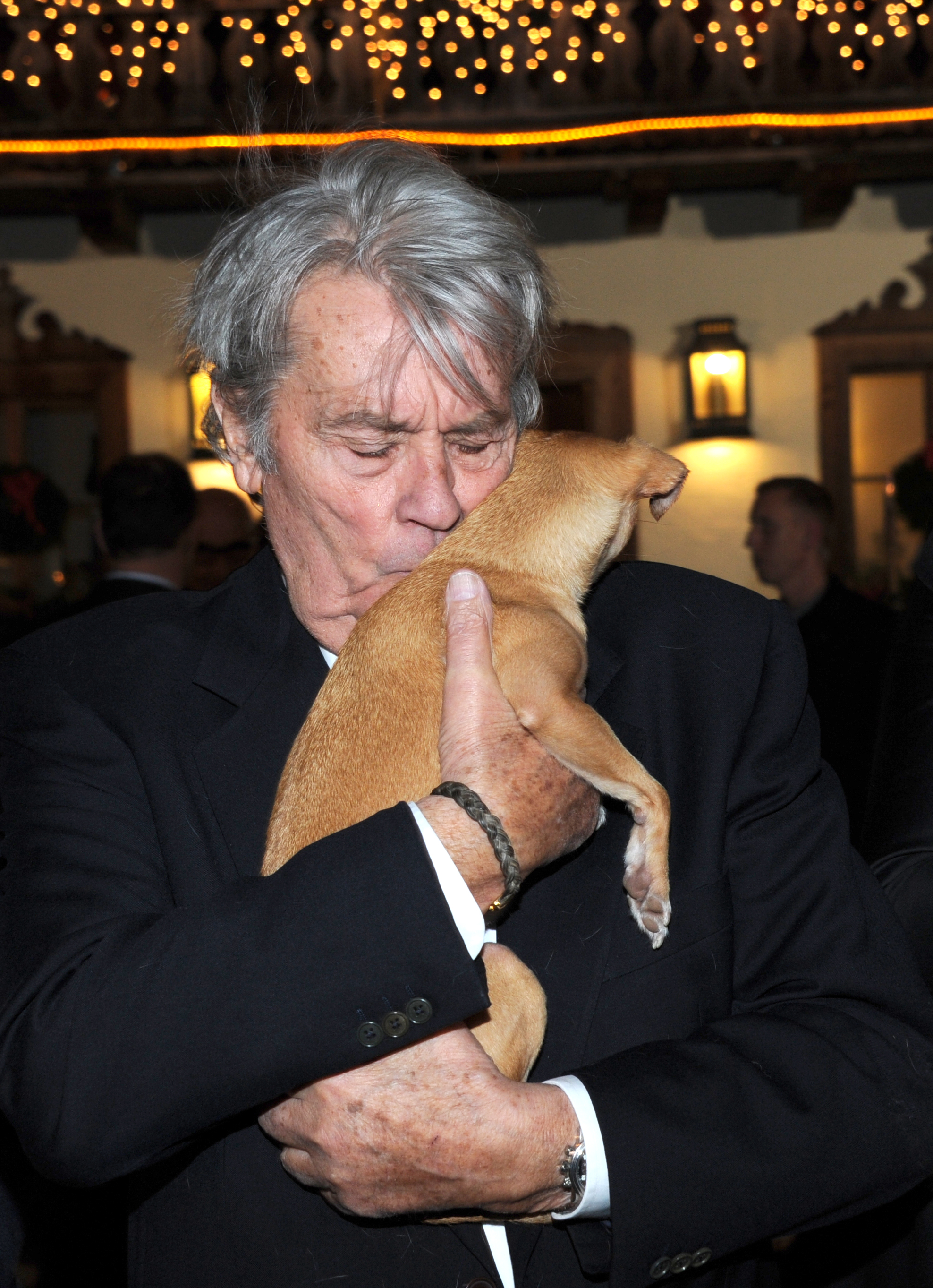 Alain Delon posant avec Molly le chien lors d'une exposition traditionnelle de Noël à Henndorf près de Salzbourg, en Autriche, le 11 novembre 2014. | Source : Getty Images