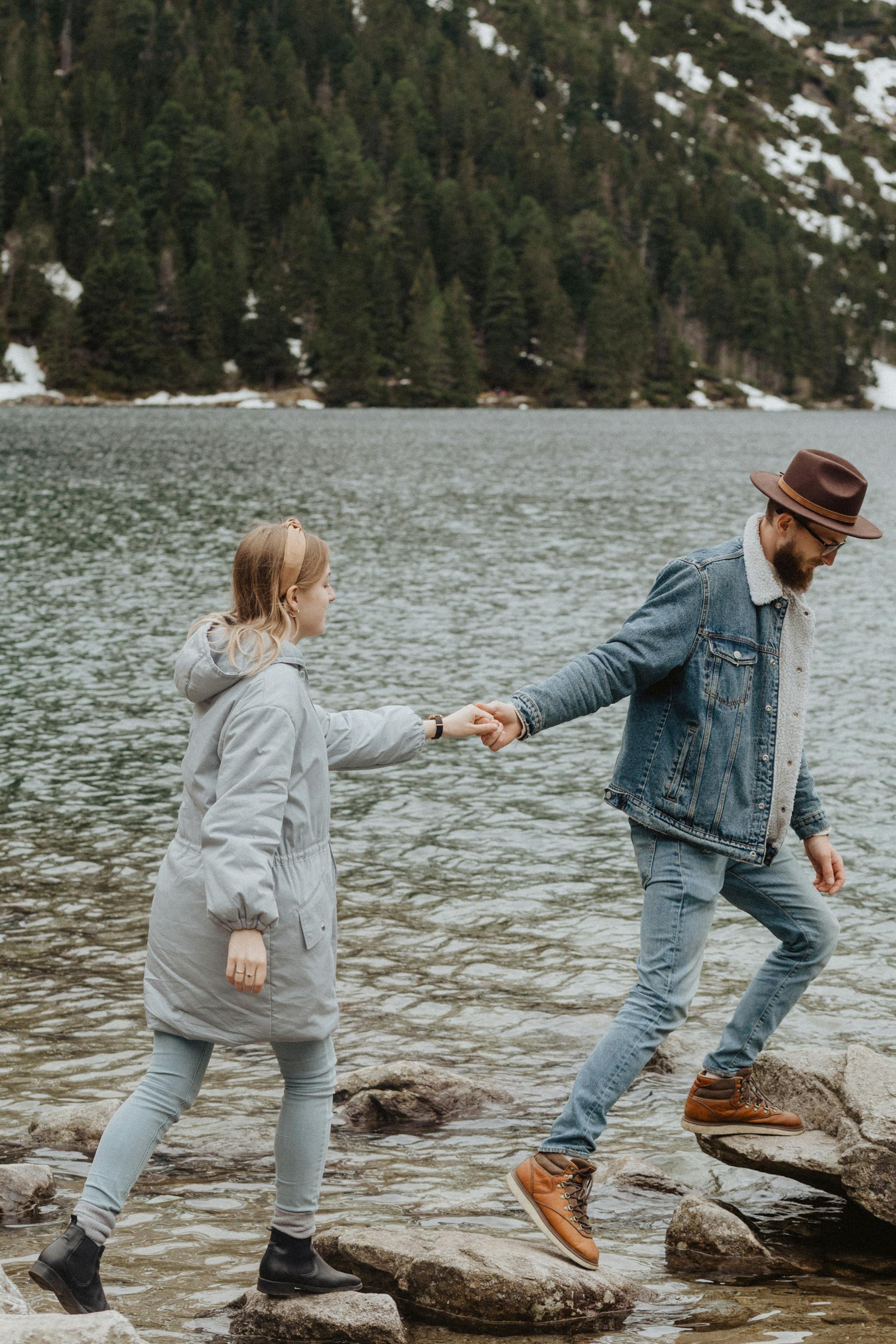 Un couple marchant sur des rochers près d'un lac | Source : Pexels