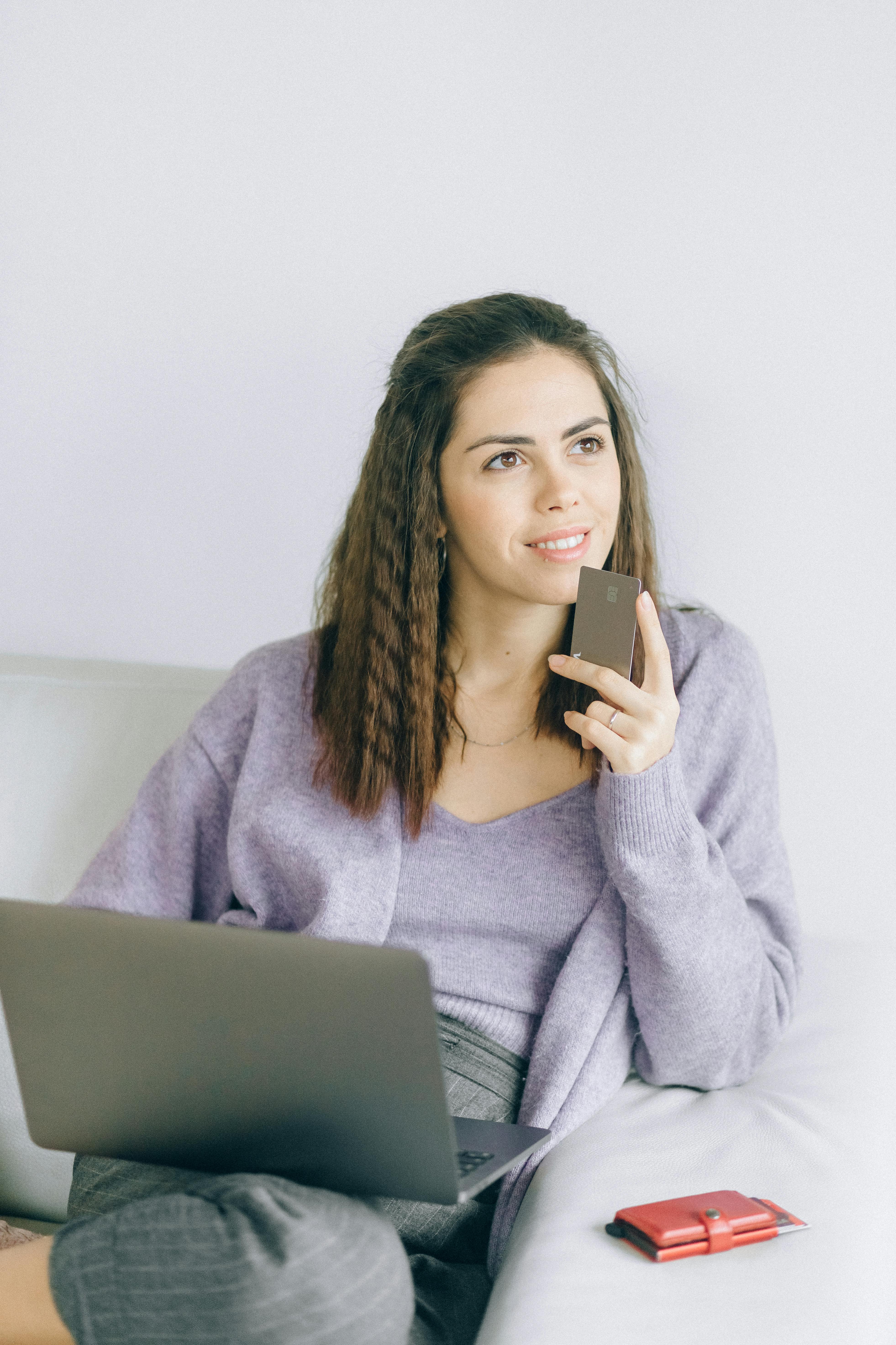 Une femme tenant une carte bancaire et un ordinateur portable | Source : Pexels