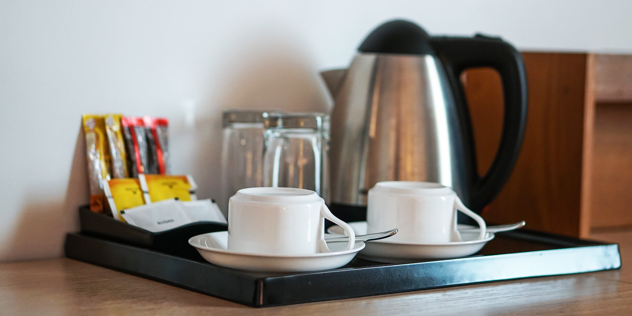 Un ensemble de boissons avec une tasse à café, une bouilloire, des verres, du thé, du café, du sucre dans une chambre d'hôtel | Source : Getty Images