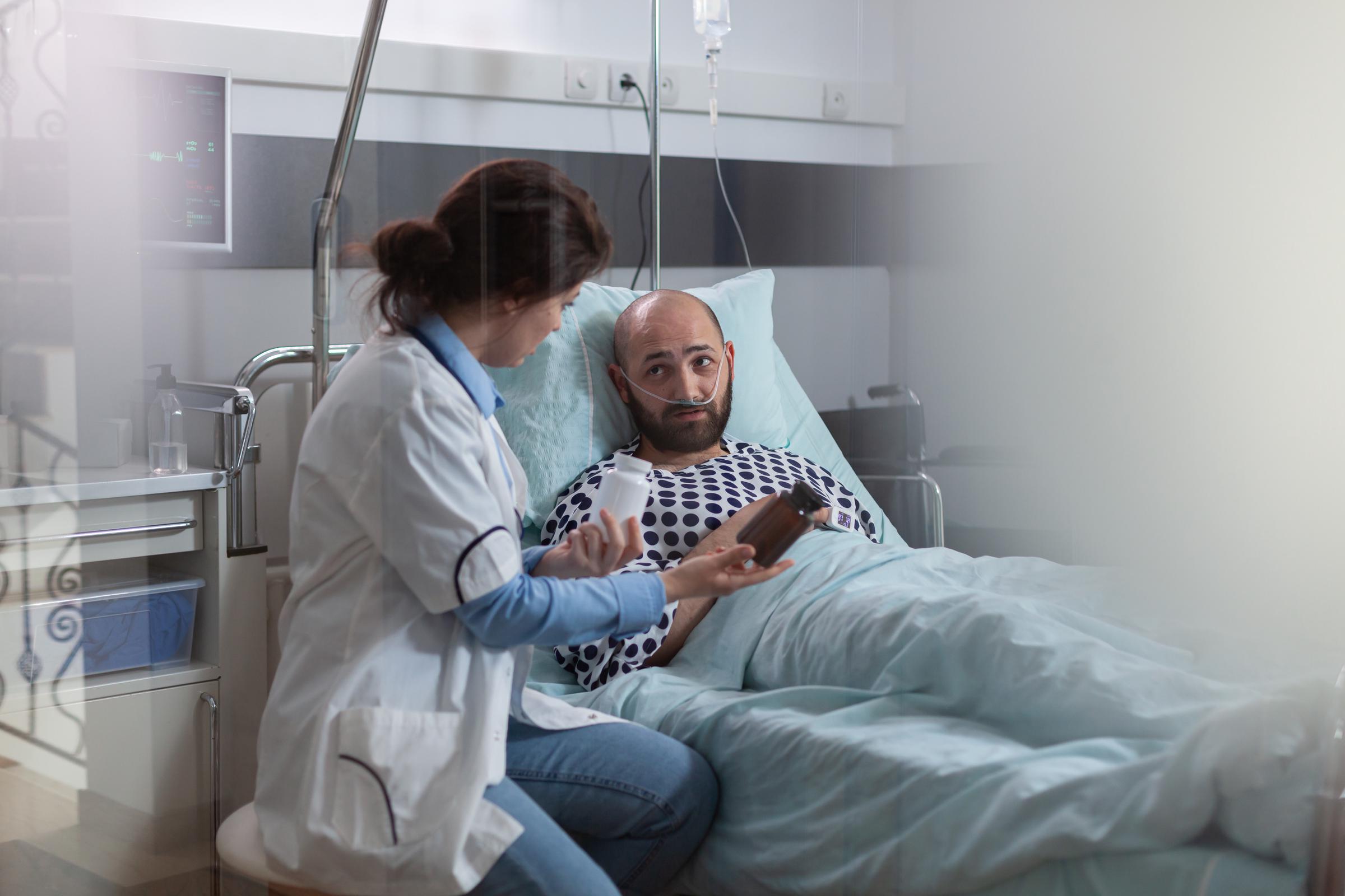 Un homme malade, équipé d'une canule nasale à oxygène, allongé dans son lit pendant un examen médical | Source : Magnific