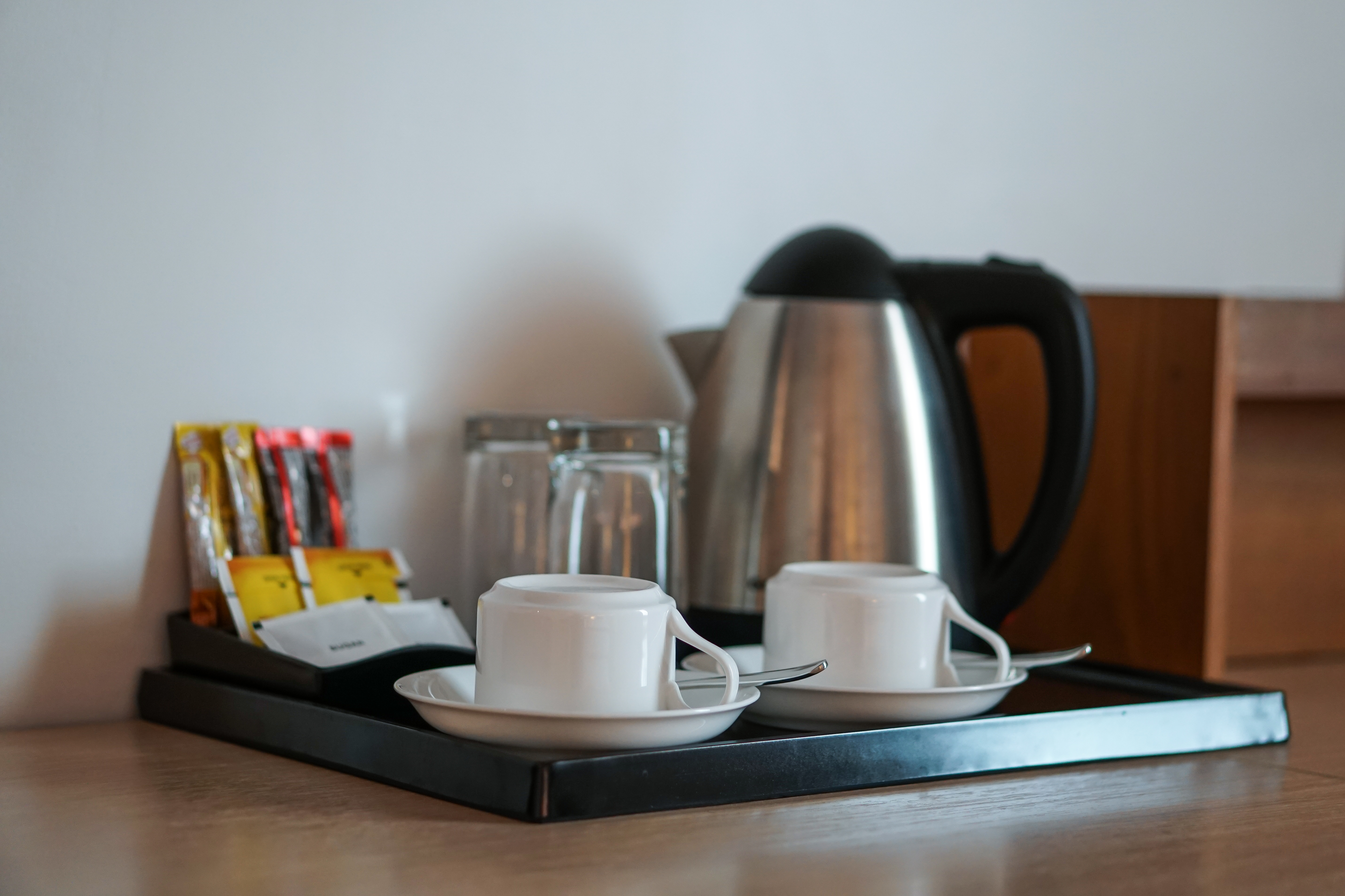 Un ensemble de boissons avec une tasse à café, une bouilloire, des verres, du thé, du café, du sucre dans une chambre d'hôtel | Source : Getty Images