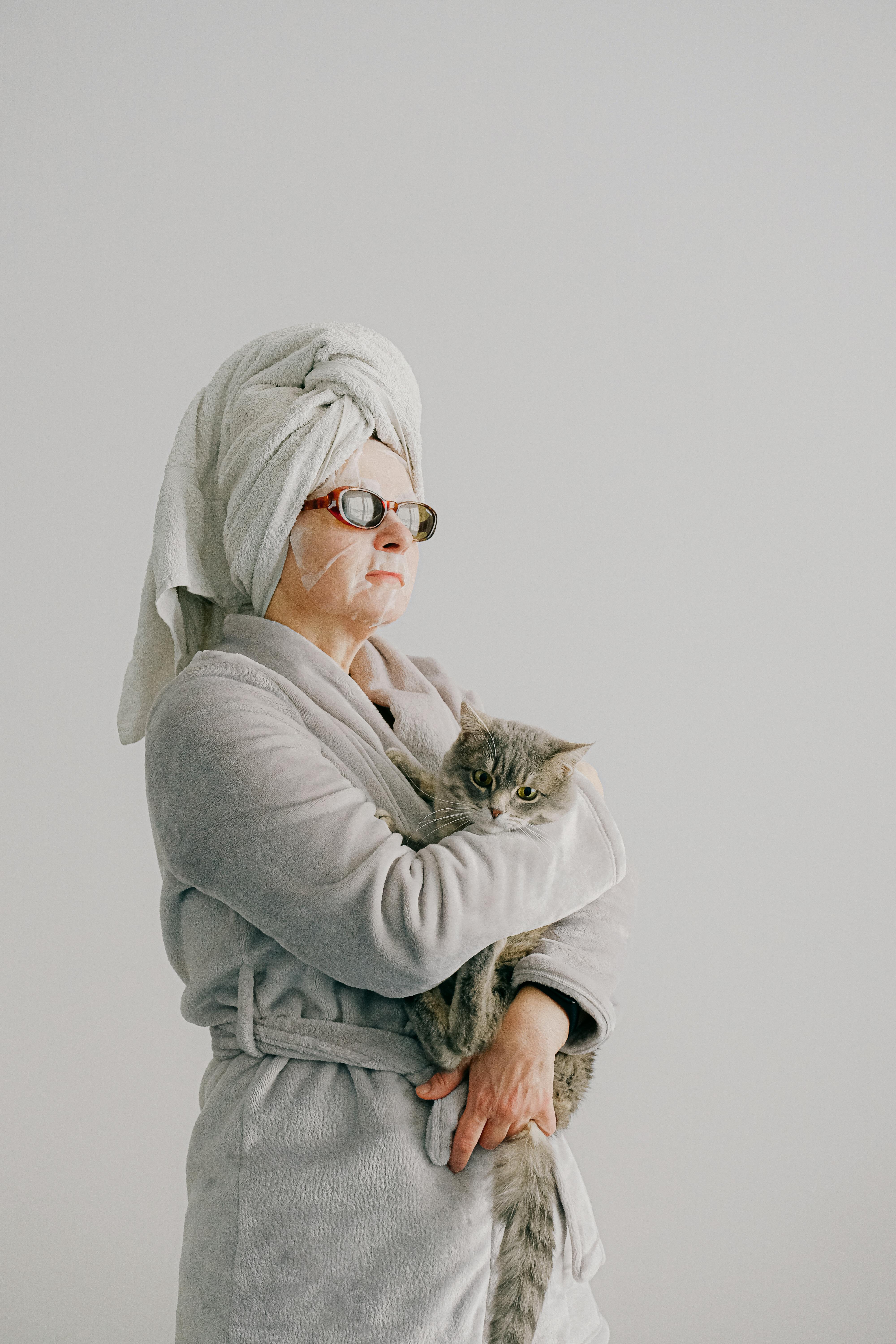 Une femme arrogante vêtue d'une robe, et de lunettes de soleil tout en tenant un chat | Source : Pexels