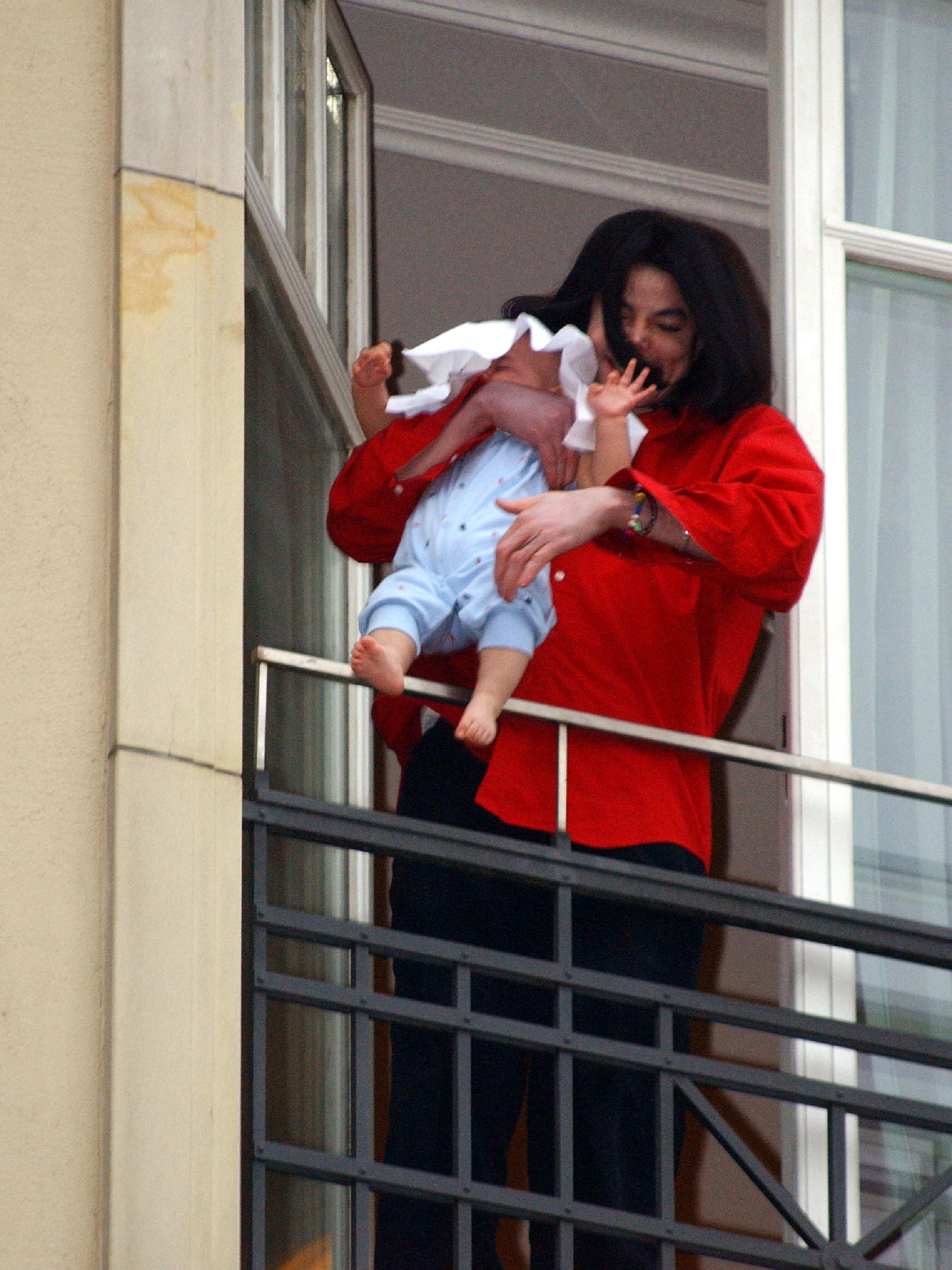 Michael Jackson tient son fils de huit mois, Prince Michael II, sur le balcon de l'hôtel Adlon | Source : Getty Images