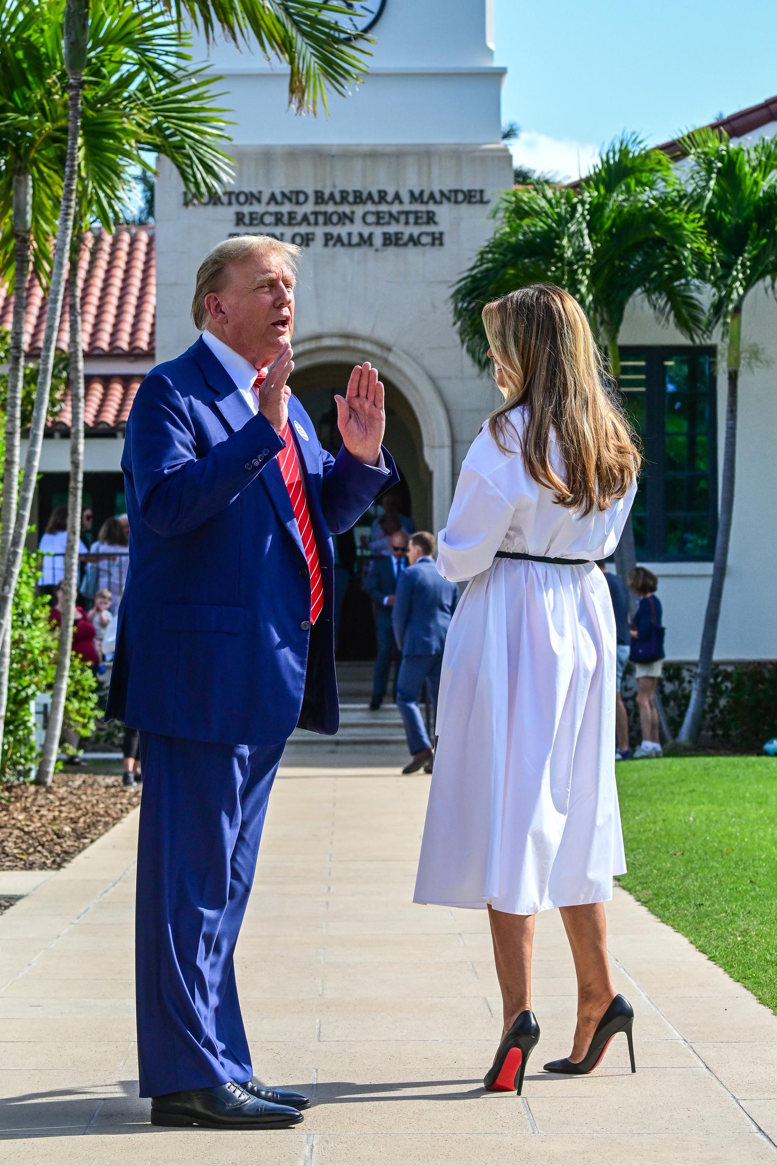 L'ancienne Première dame Melania Trump discute avec Donald Trump alors qu'ils arrivent pour voter lors de la primaire présidentielle en Floride, au Morton and Barbara Mandel Recreation Center à Palm Beach, en Floride, le 19 mars 2024. Elle porte une robe mi-longue blanche impeccable à col, cintrée à la taille par une fine ceinture noire, et accessoirisée d’escarpins Christian Louboutin en cuir verni noir à bout pointu, dotés de talons aiguilles vertigineux et de semelles laquées d’un rouge vif.