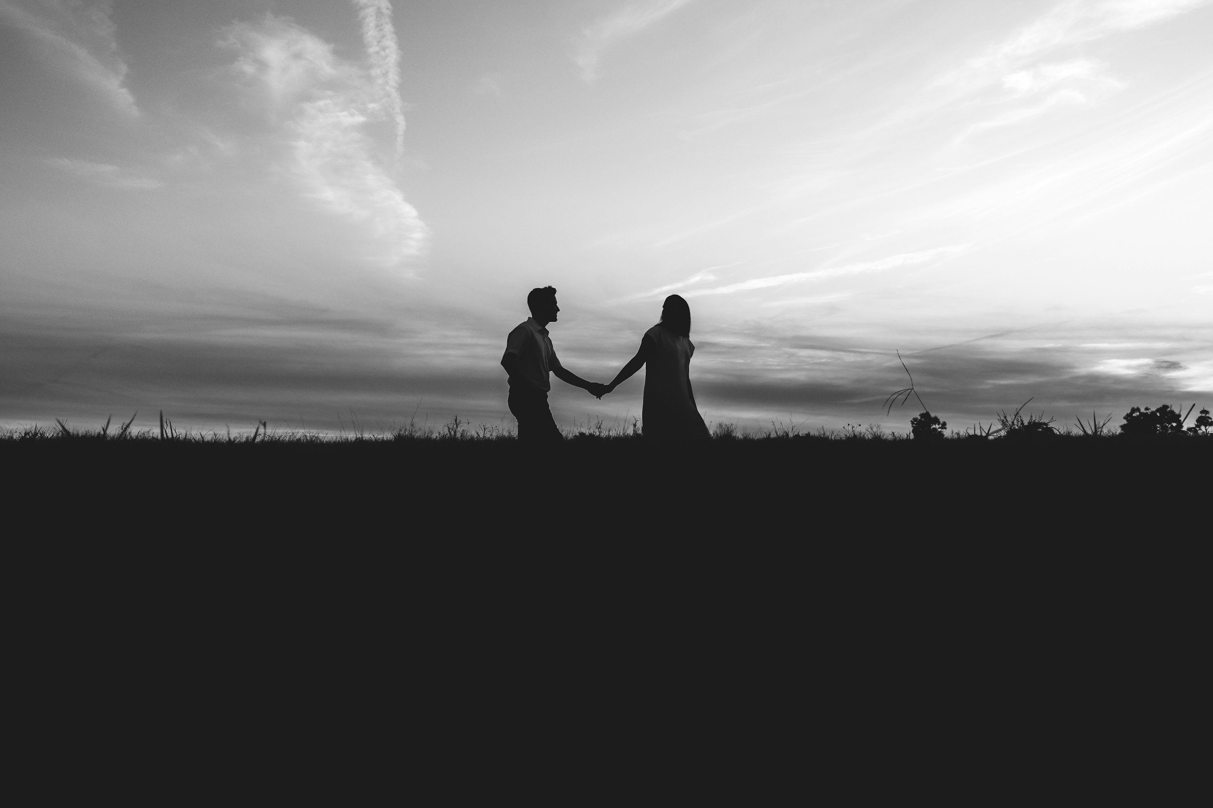 Silhouette d'un couple se tenant par la main et marchant | Source : Unsplash