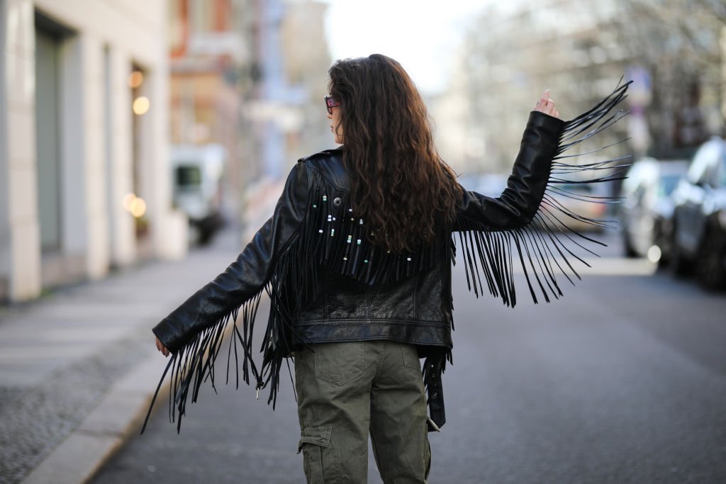 Une femme filmée de dos et portant une veste en cuir avec des franges. | Photo : Getty Images