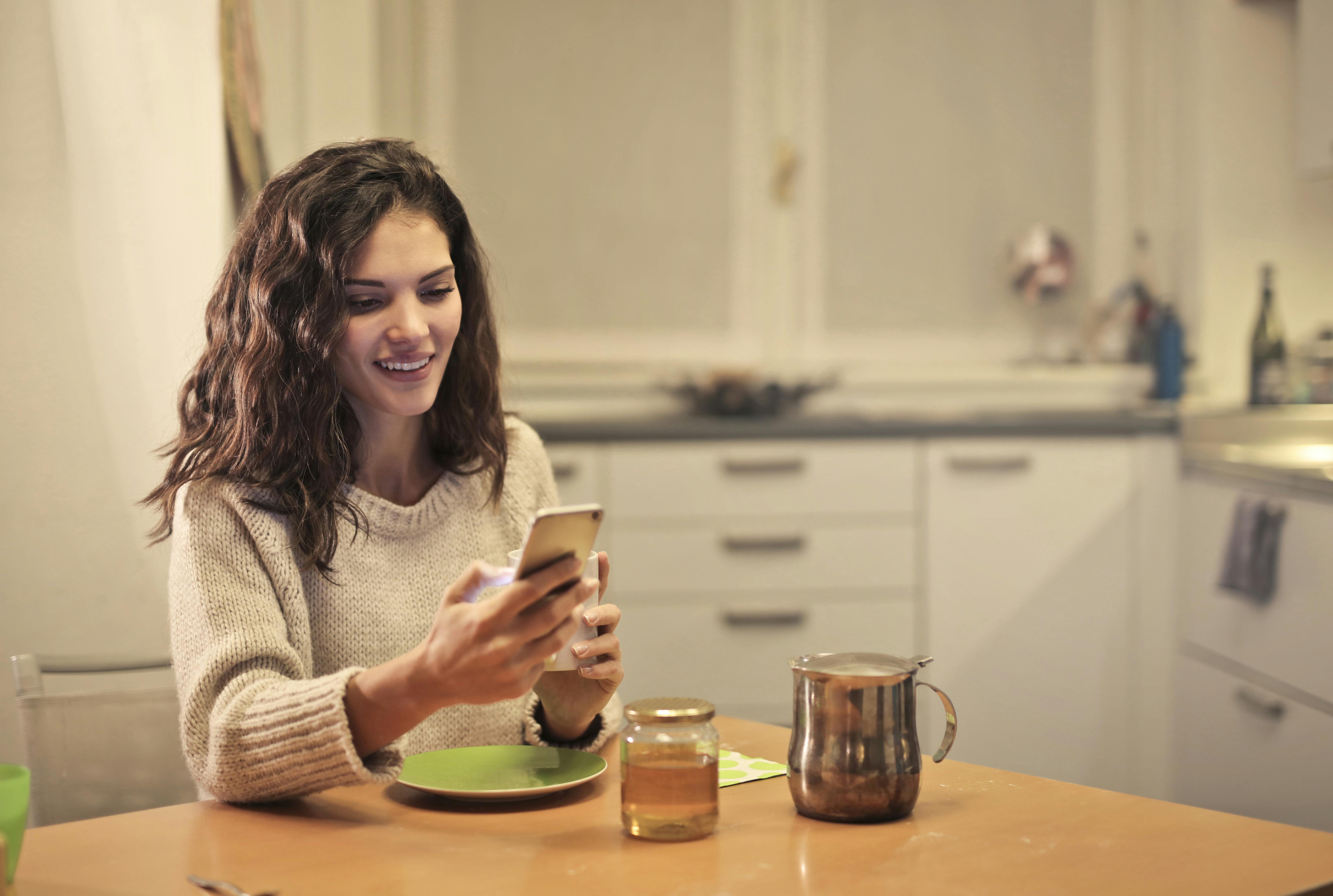 Une femme heureuse qui regarde son téléphone | Source : Pexels