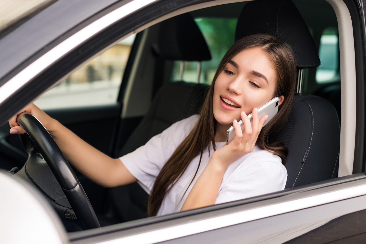 Une femme ravie, assise dans sa voiture et parlant au téléphone | Source : Freepik