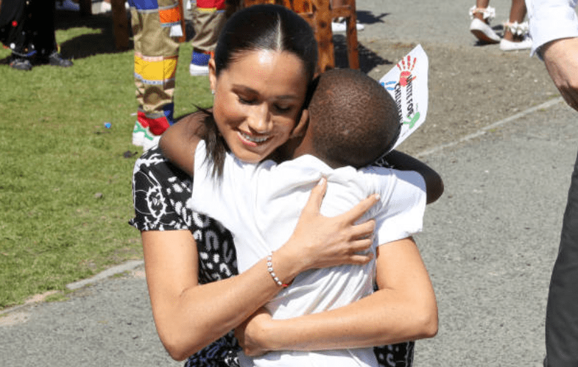 Au cours de sa tournée en Afrique avec le prince Harry, Meghan Markle embrasse un jeune à l'initiative Justice Desk dans le township de Nyanga, le 23 septembre 2019, au Cap, en Afrique du Sud | Getty Images