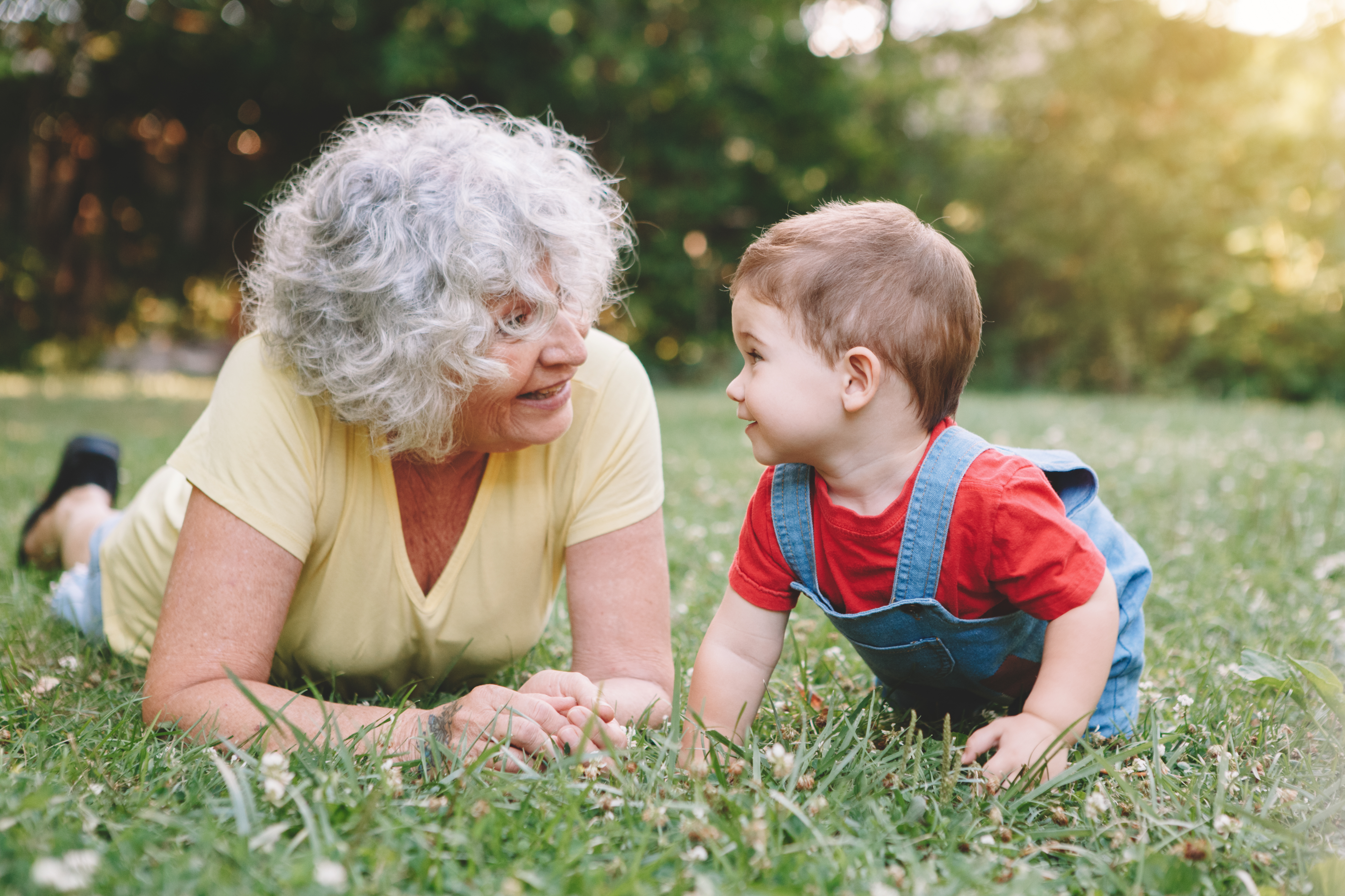 Une grand-mère et un petit-enfant allongés dans l'herbe | Source : Shutterstock