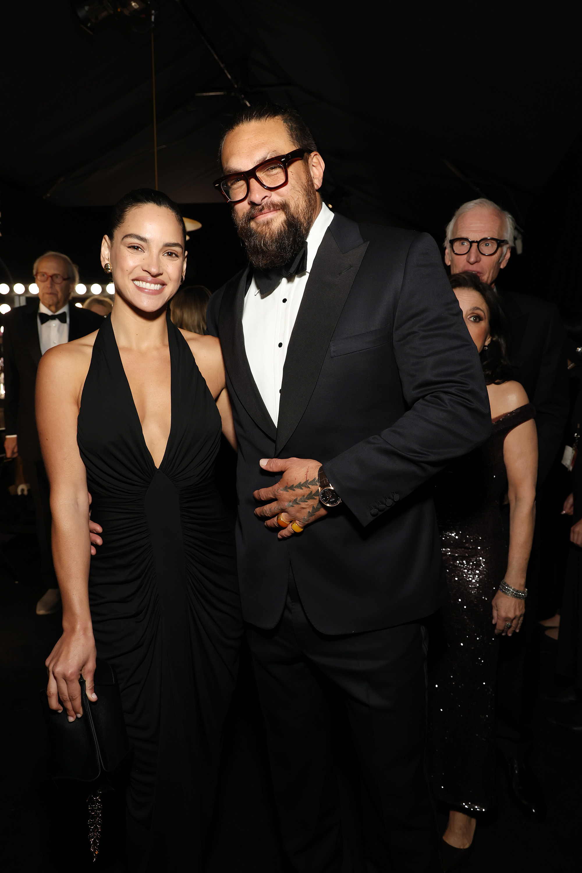 Adria Arjona et Jason Momoa sourient devant les caméras. | Source : Getty Images