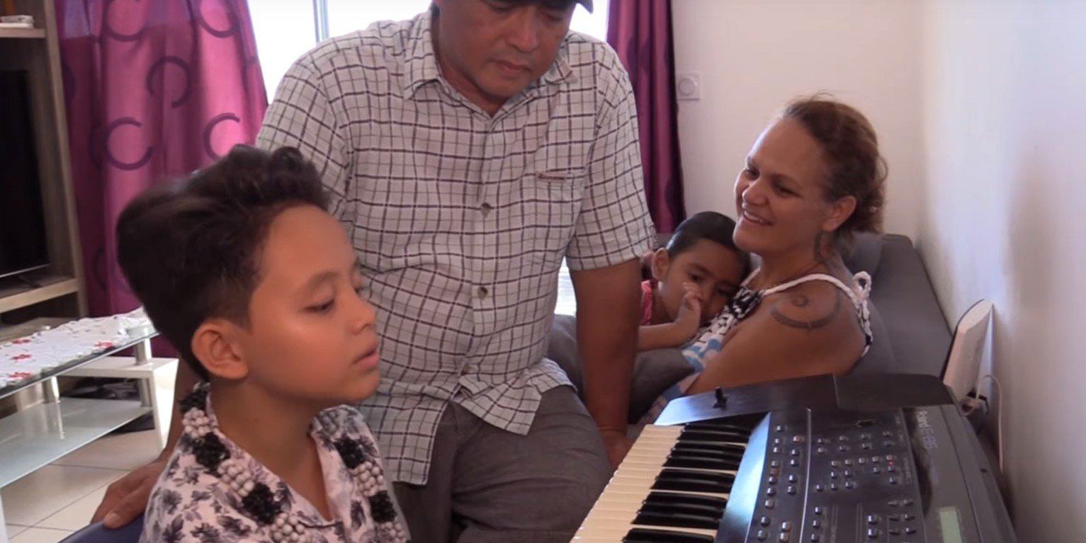 Natihei jouant du piano et chantant pour le plus grand plaisir de sa famille. l Source : YouTube/Tahiti Nui Télévision