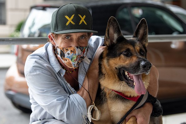 Le photographe David Allen portant un masque à empreintes de chiens pose avec son berger allemand.|Photo : Getty Images