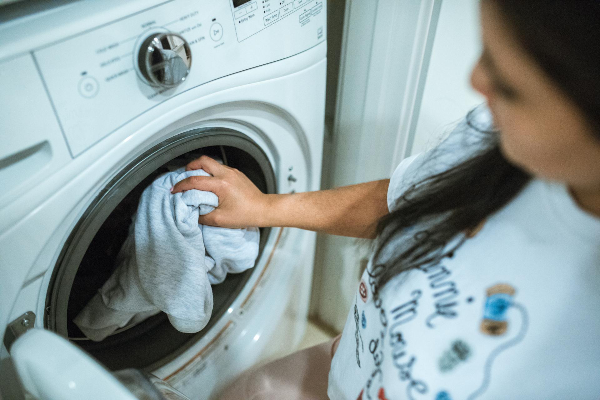 Femme jetant des vêtements dans la machine à laver | Source : Pexels