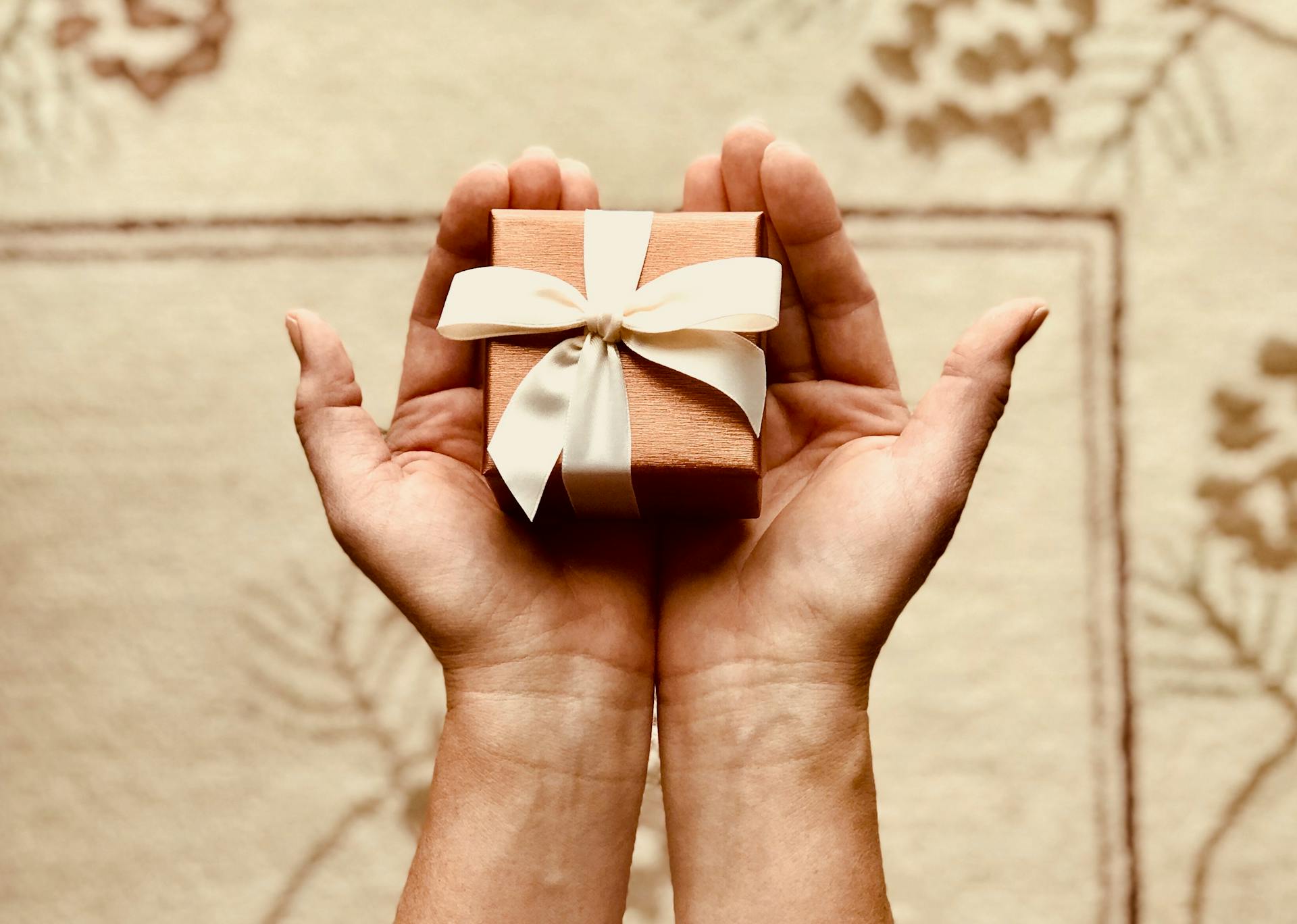 Gros plan d'une femme tenant un petit paquet cadeau marron | Source : Pexels