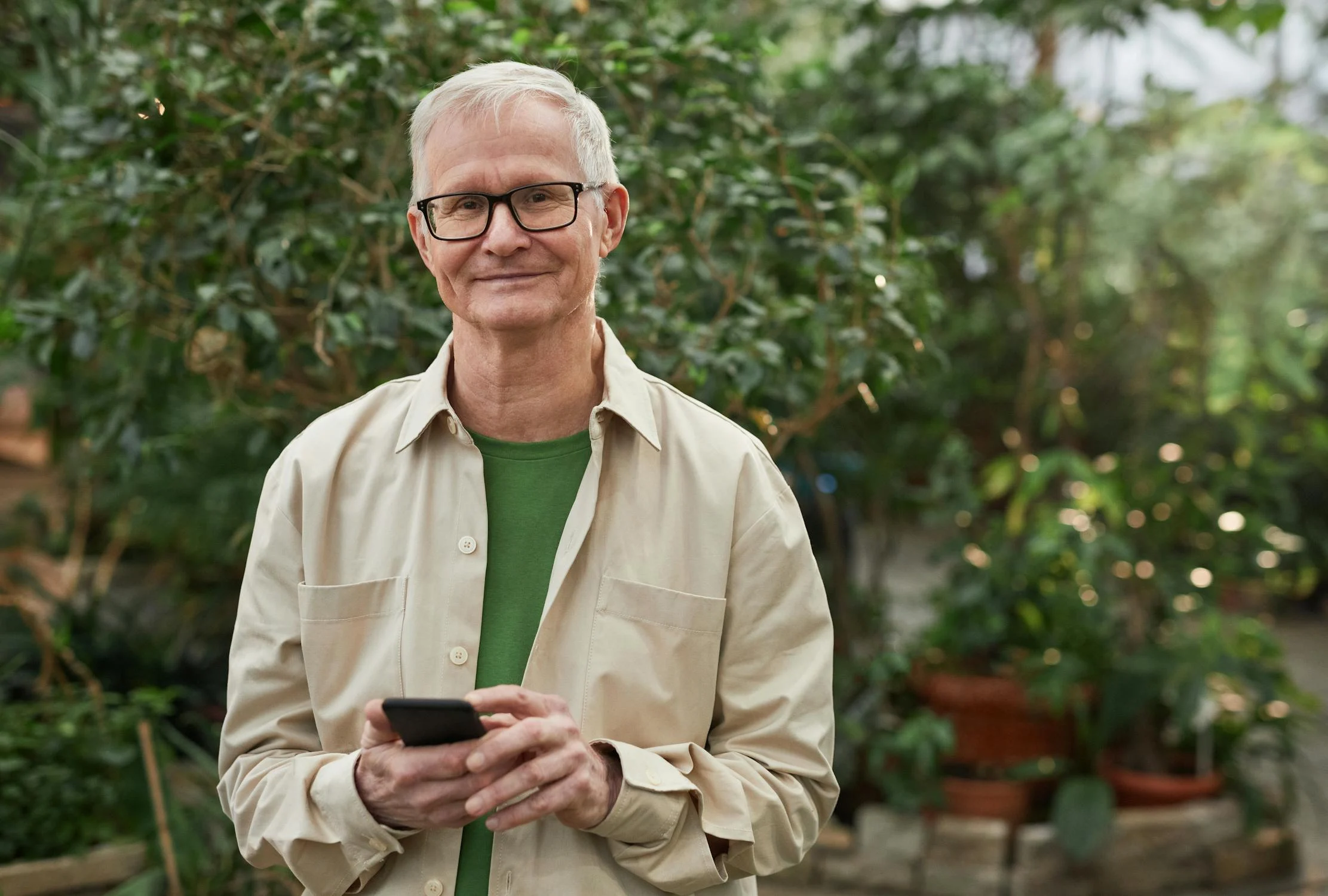 Un homme souriant tenant son téléphone ⏐ Source : Pexels