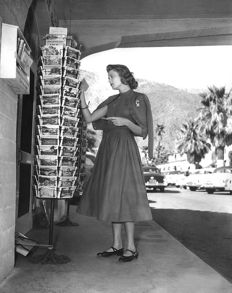 L'actrice Grace Kelly regardant des cartes postales à Palm Springs, Californie en 1954. | Photo : Getty Images