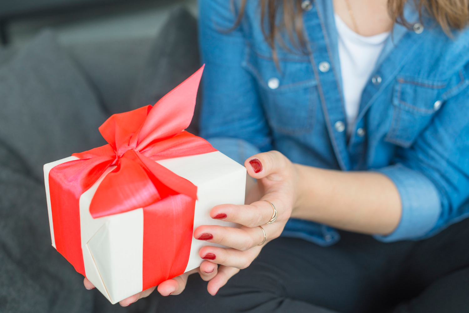 Une jeune femme tenant un cadeau soigneusement emballé et orné d'un ruban rouge vif | Source : Freepik