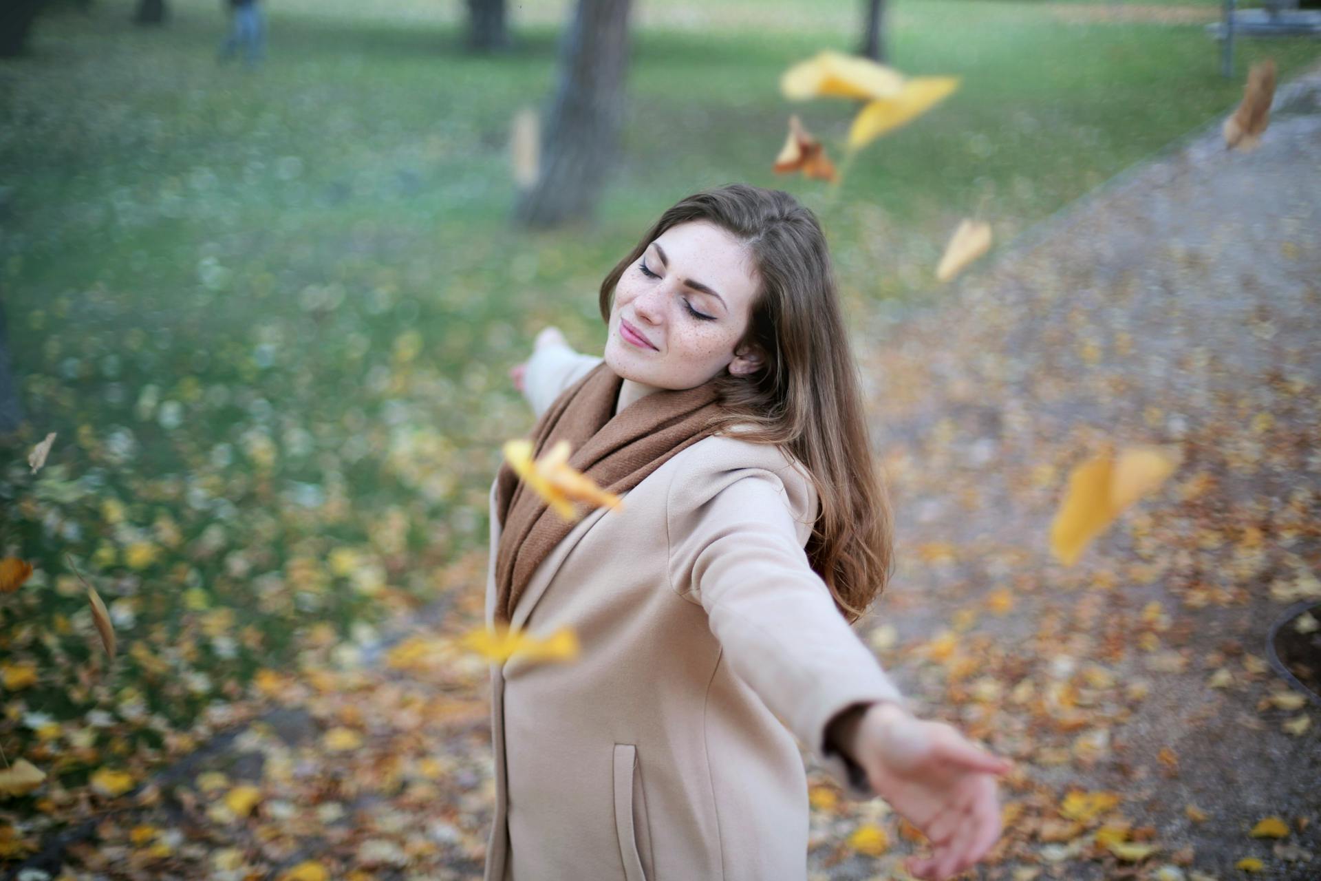 Une jeune femme souriant les yeux fermés et les bras grands ouverts | Source : Pexels