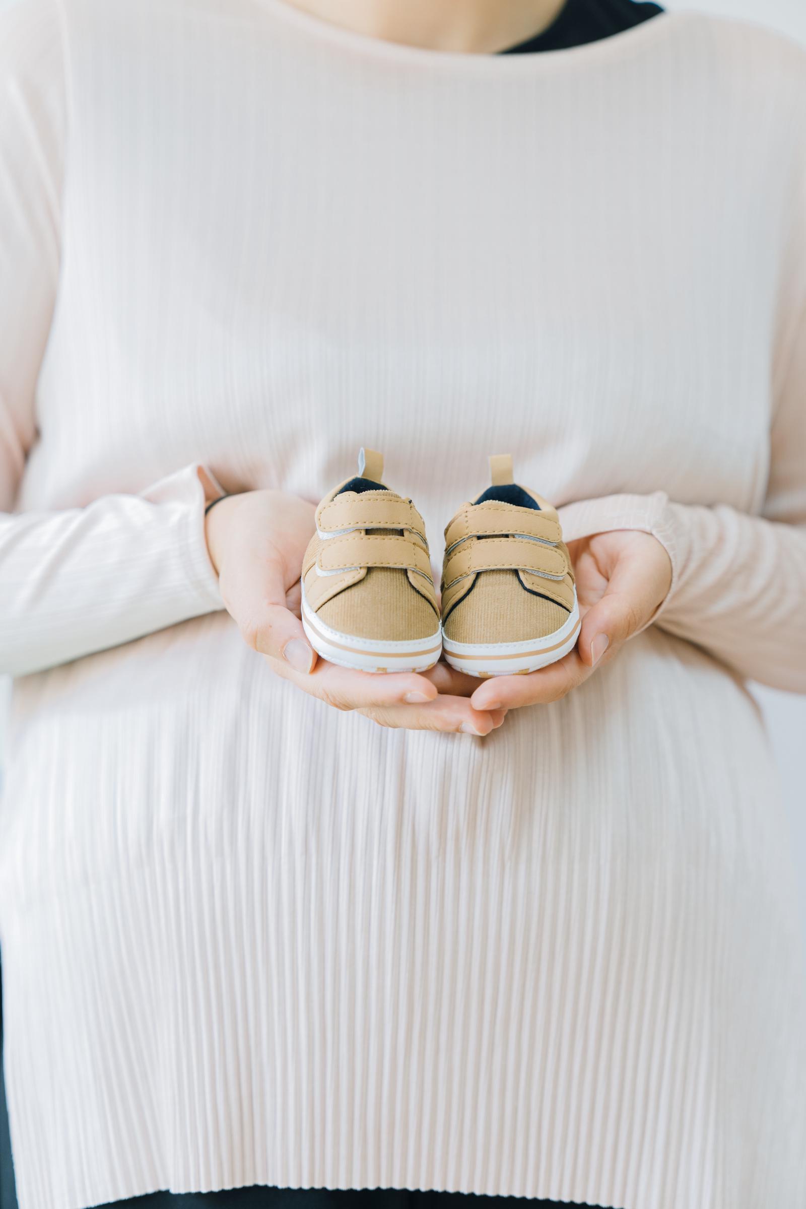 Une femme tenant de minuscules chaussures de bébé | Source : Freepik