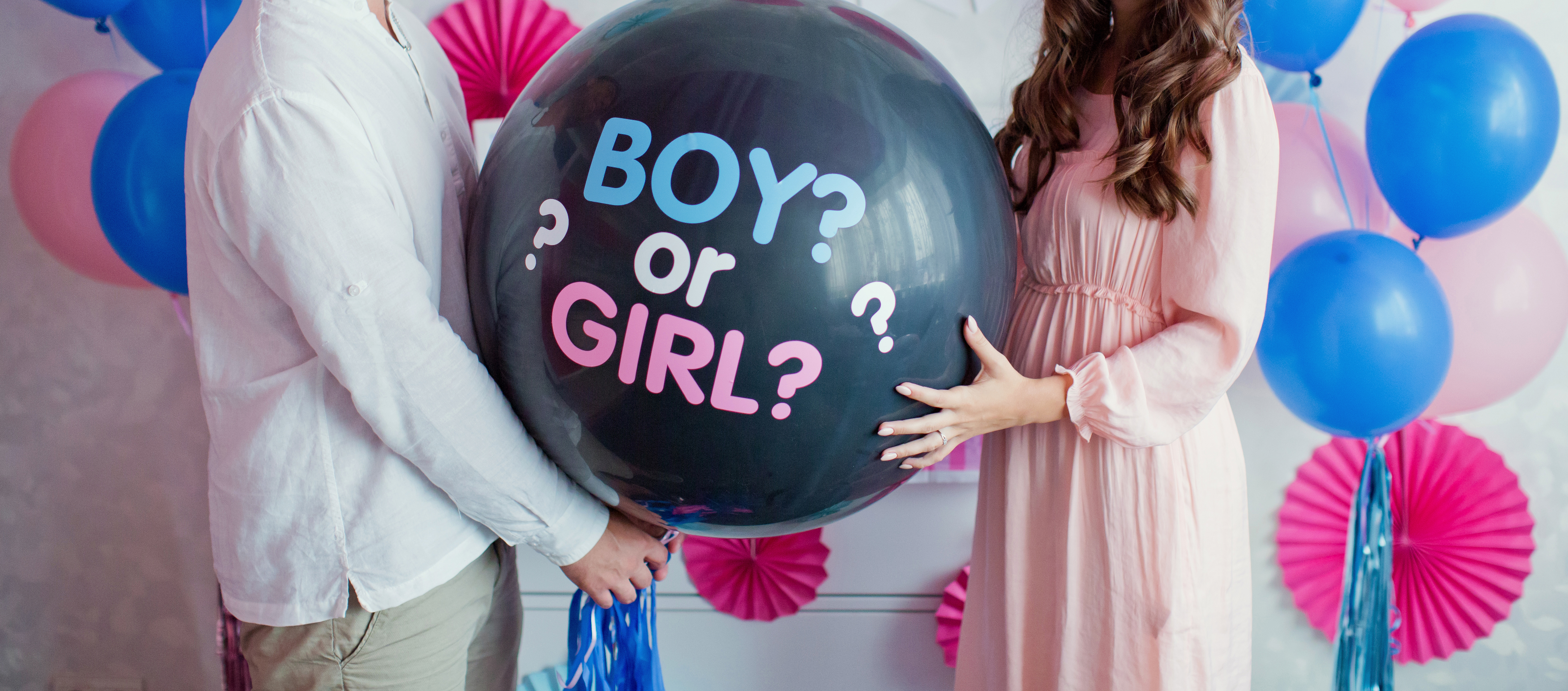 Un homme et une femme tenant un ballon noir avec "garçon ou fille ?" lors d'une fête de révélation du sexe | Source : Shutterstock