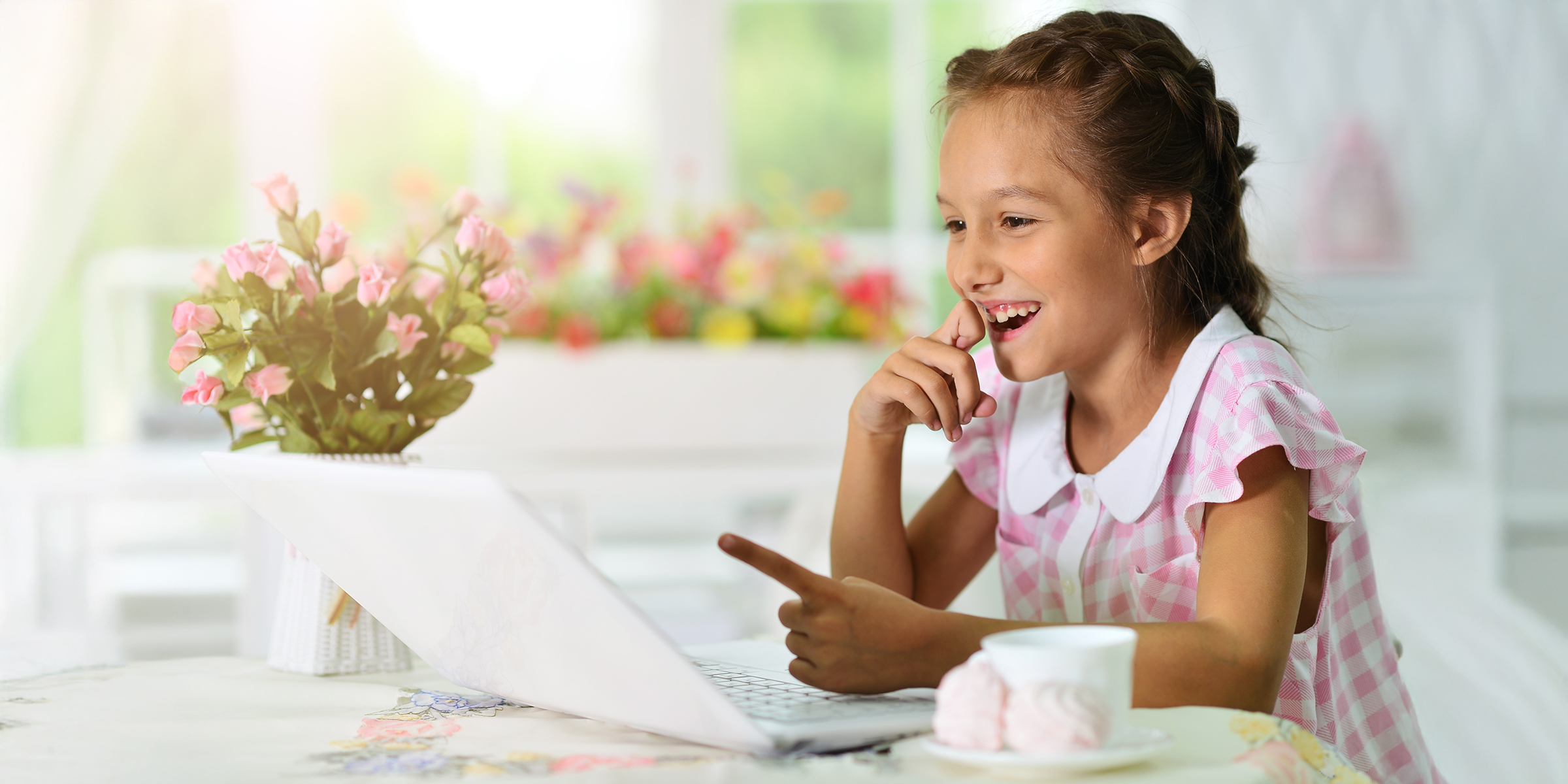 Une fille souriante pointant du doigt l'écran d'un ordinateur portable | Source : Shutterstock