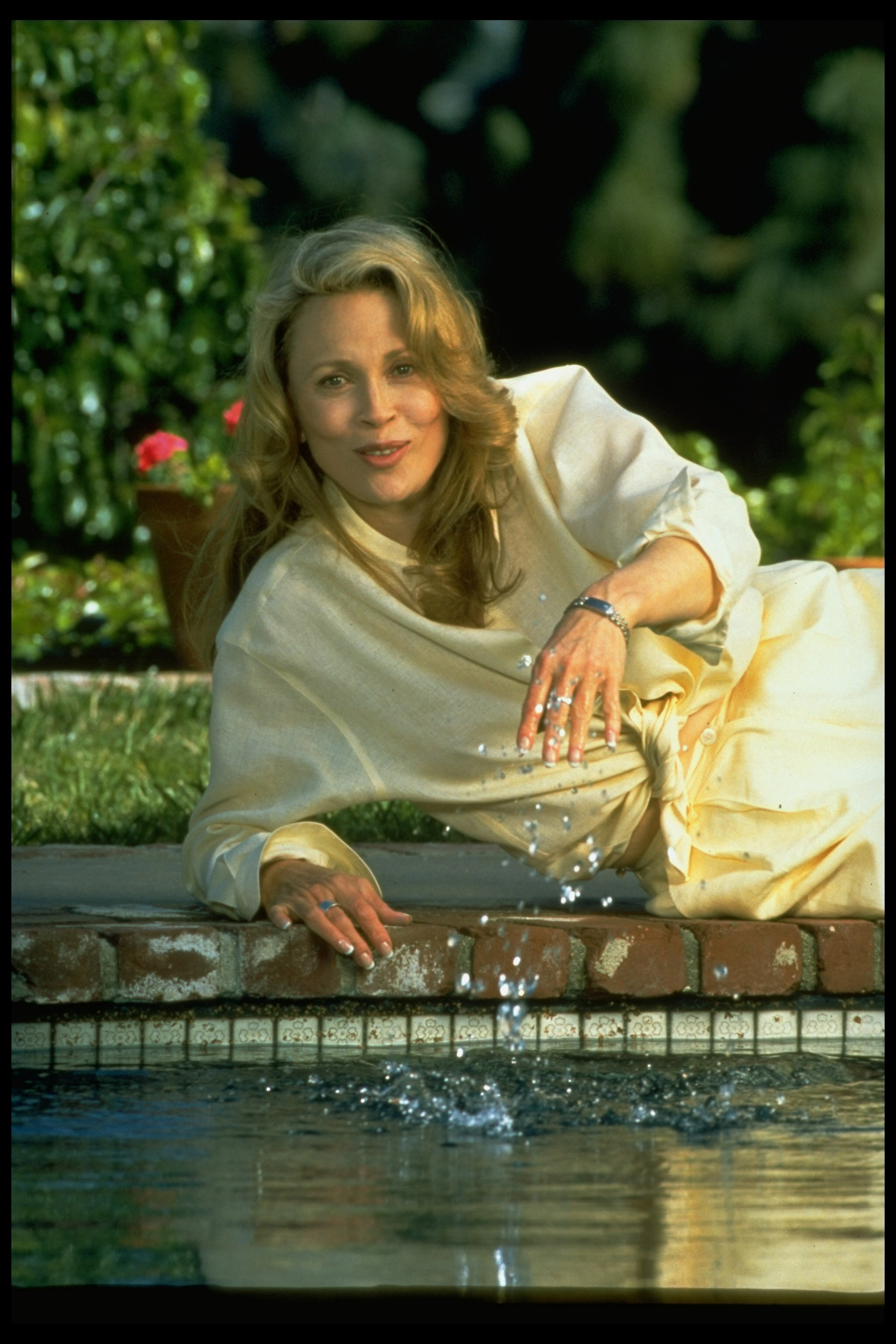 Faye Dunaway allongée sur le côté au bord de la piscine de sa maison d'Hollywood en 1995 | Source : Getty Images