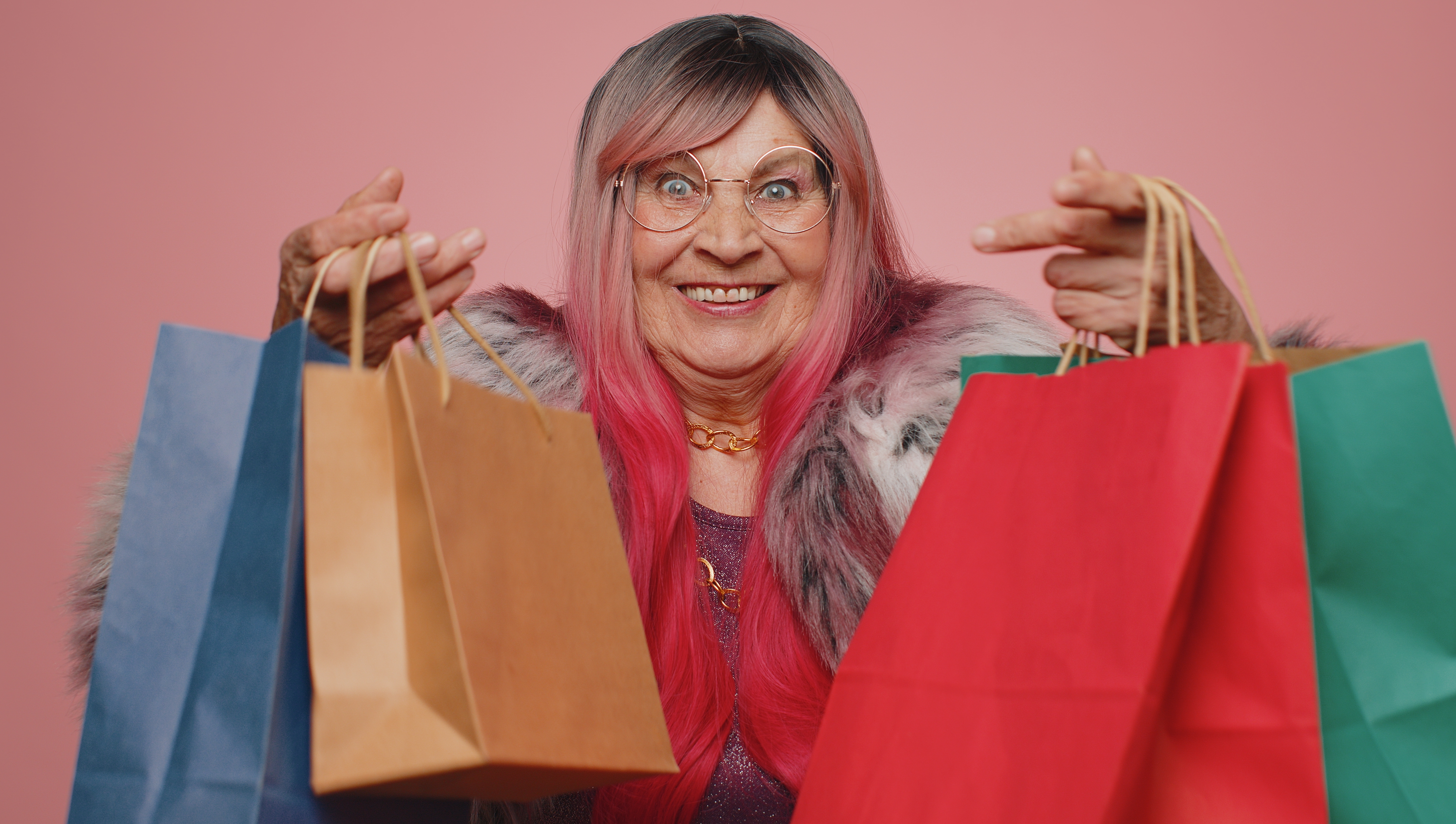 Une femme âgée qui sourit en tenant des sacs de shopping | Source : Shutterstock