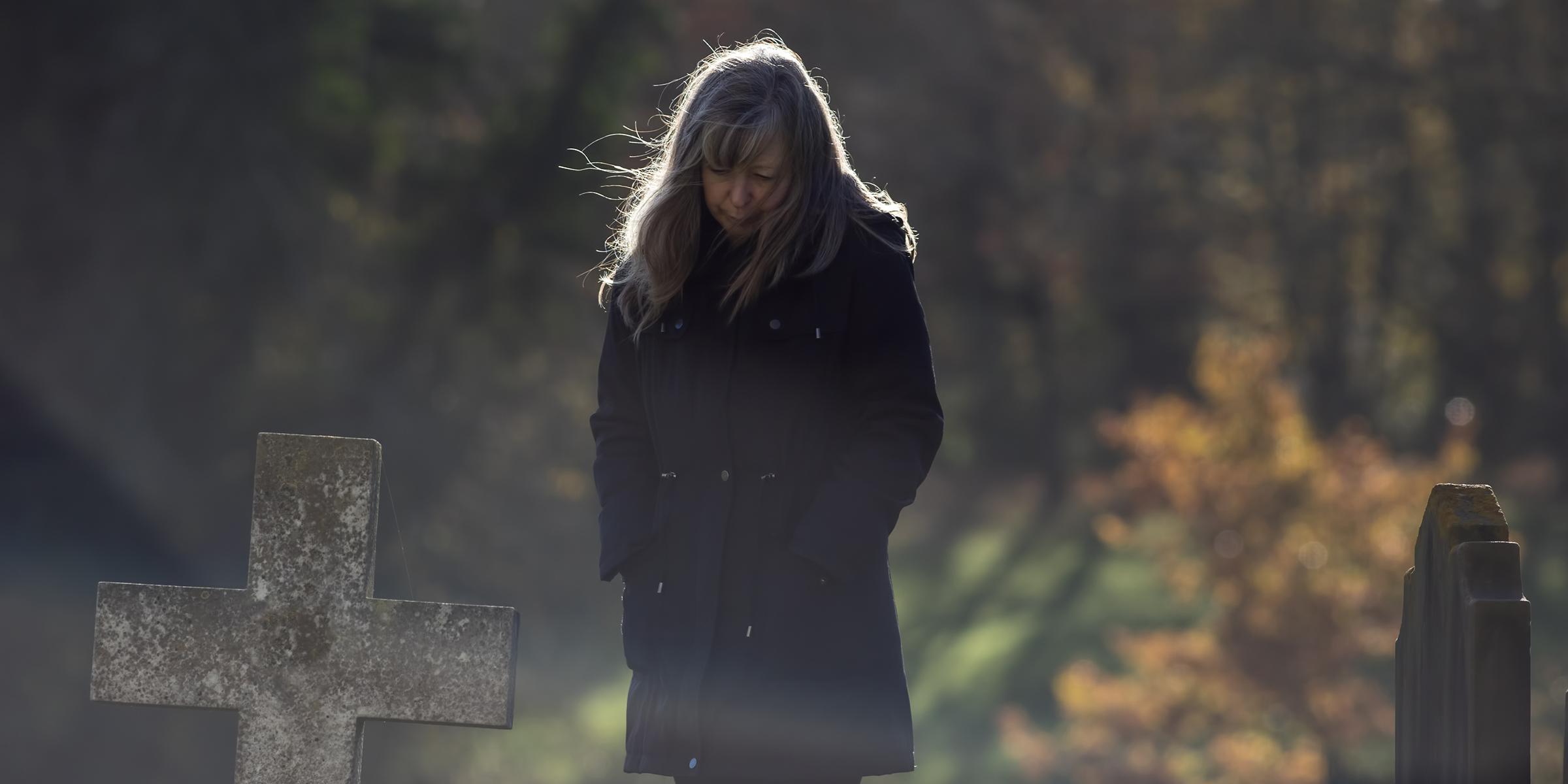 Une femme en deuil près d'une pierre tombale ⏐ Source : Shutterstock