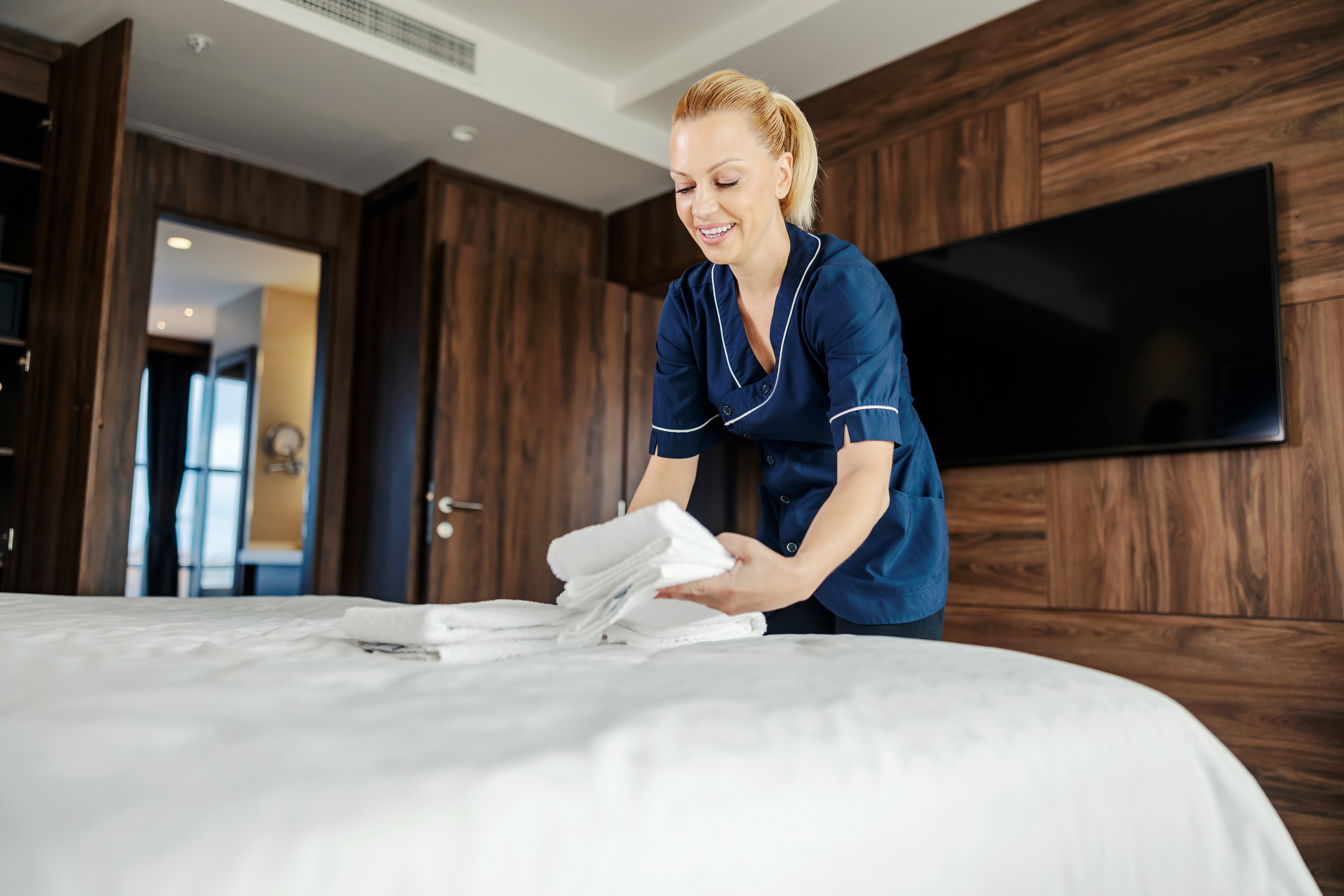 Une employée met des serviettes propres sur un lit dans une chambre d'hôtel | Source : Shutterstock