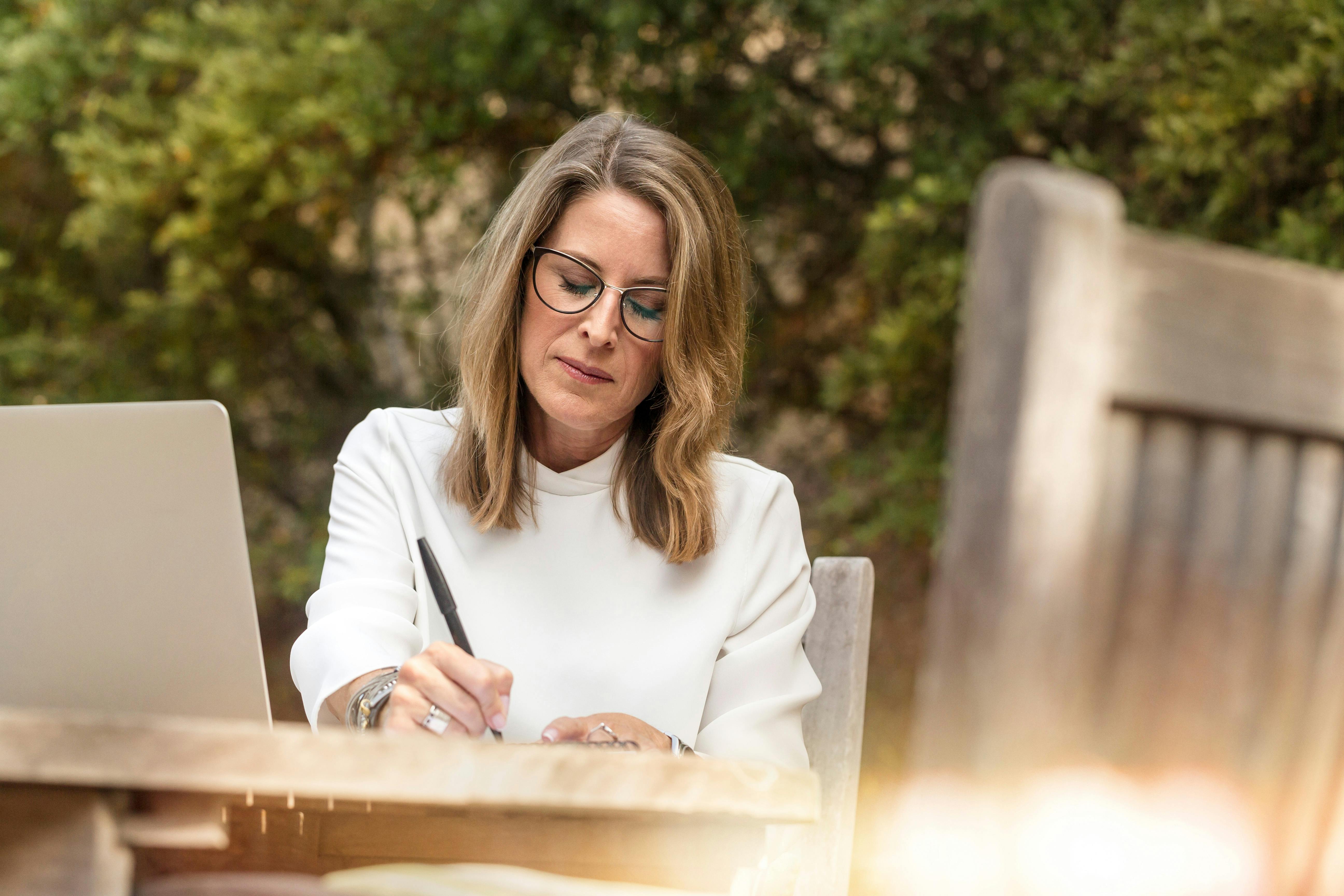 Une femme qui écrit sur sa table de jardin | Source : Pexels