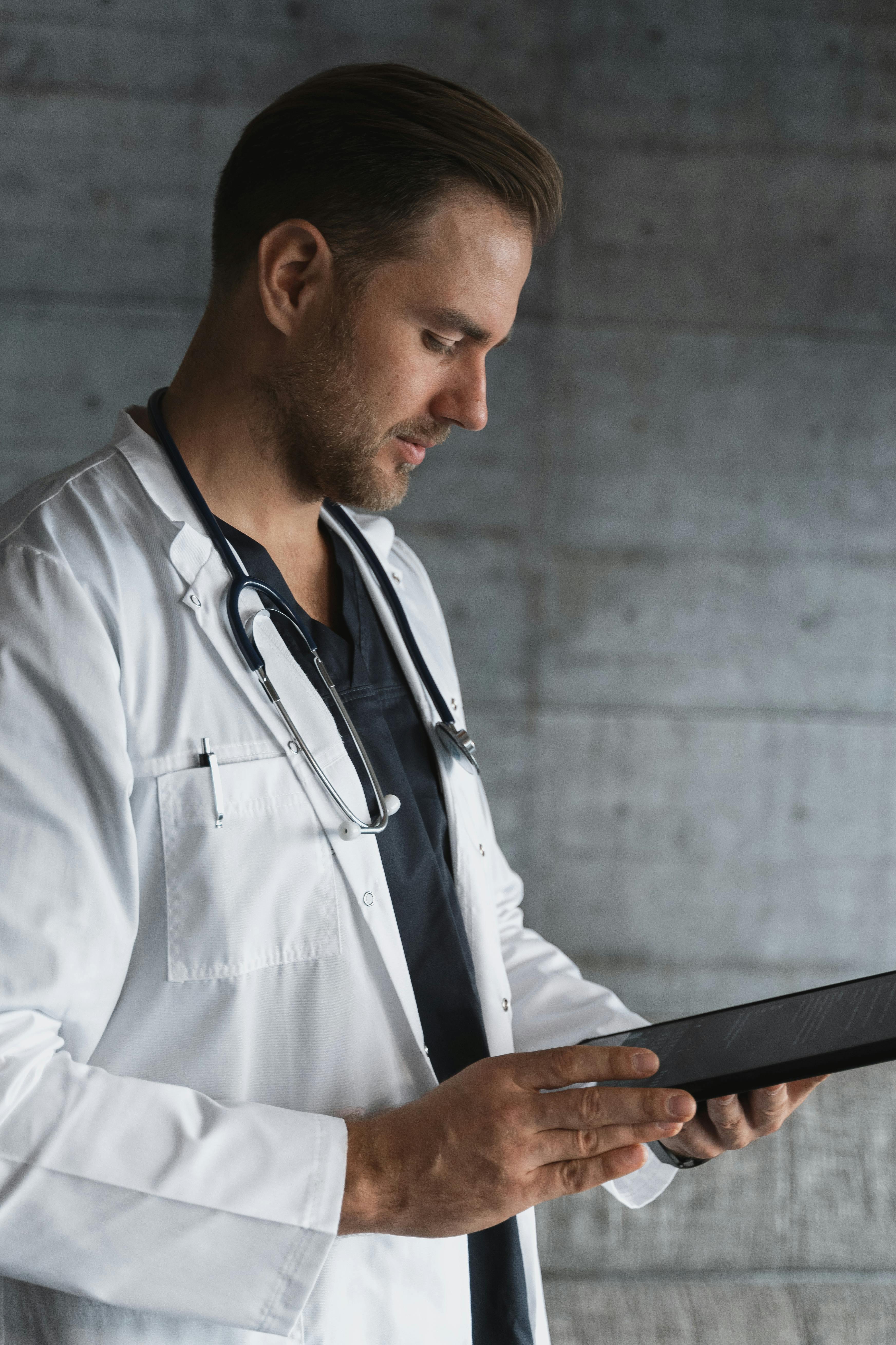 Un médecin en blouse blanche lisant des documents | Source : Pexels