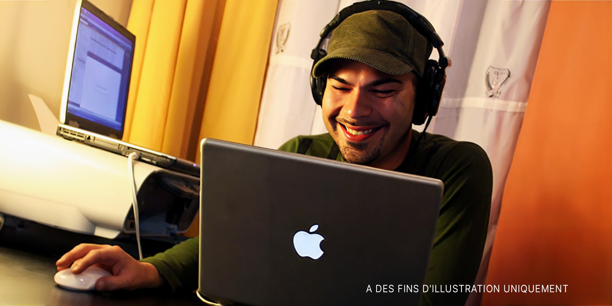 Un homme portant des écouteurs sourit à un ordinateur portable | Source : Flickr