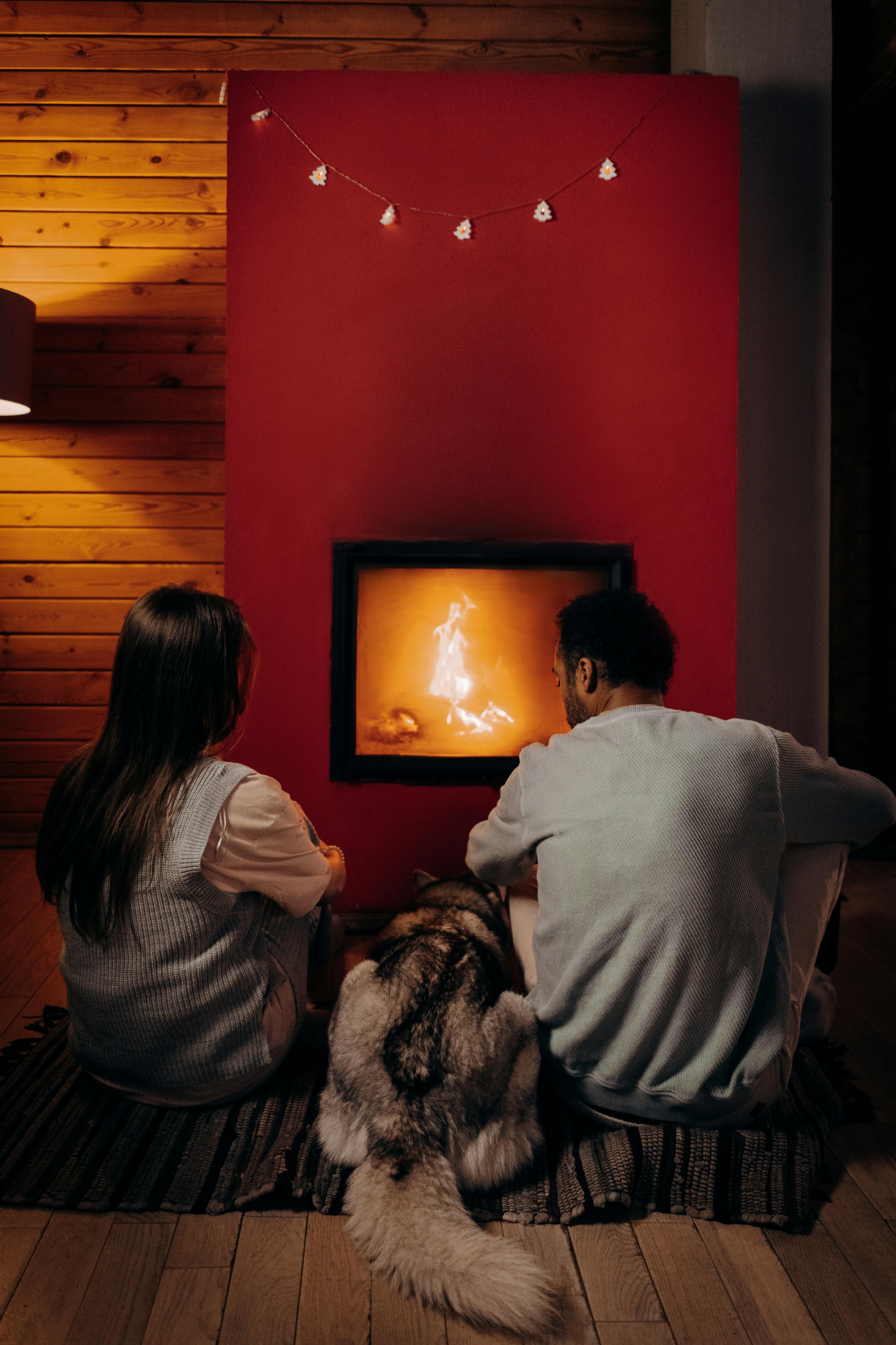 Un couple assis près de la cheminée avec un chien | Source : Pexels